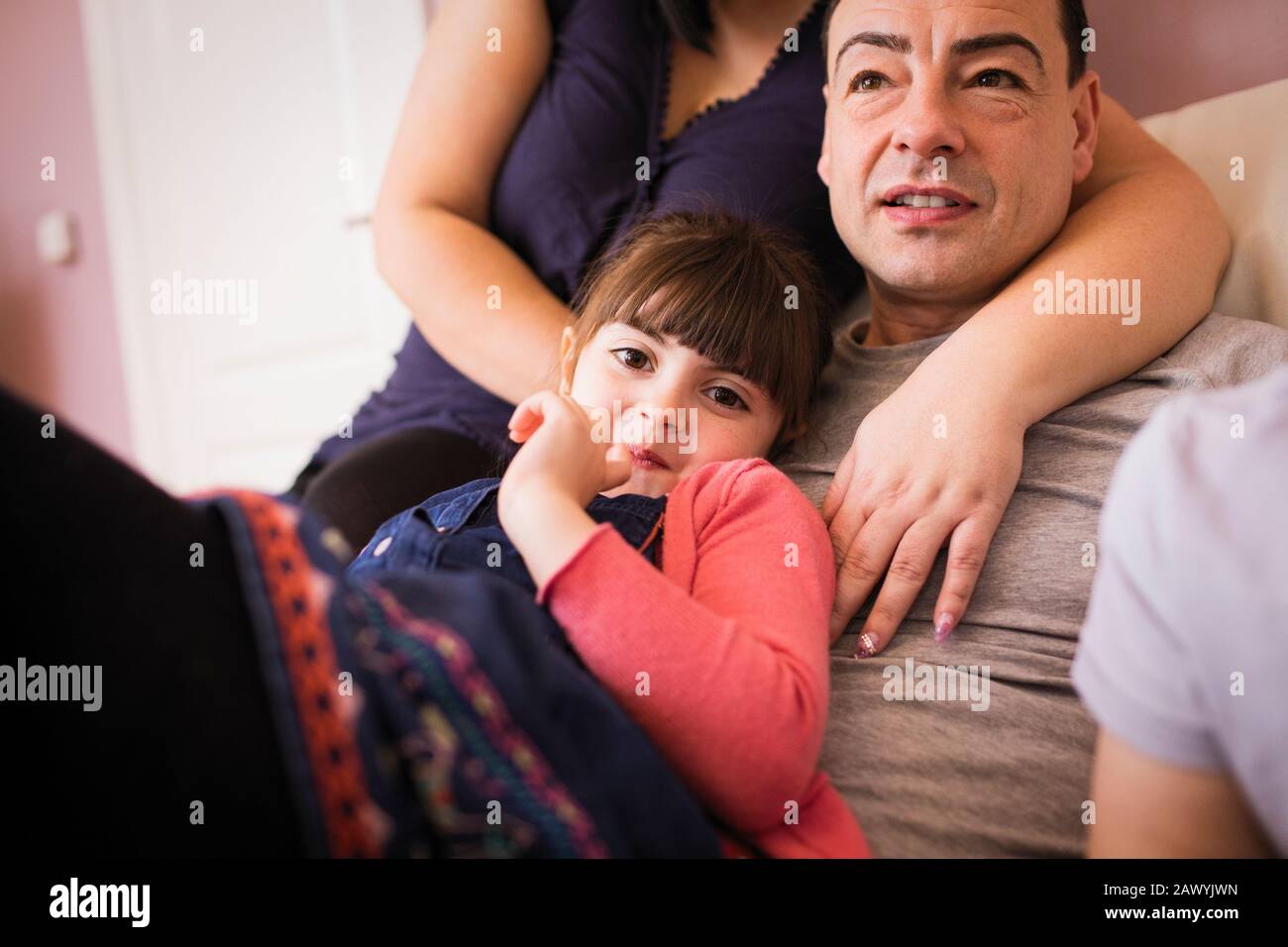Glückliches Mädchen, das mit dem Vater auf dem Sofa kuschelt Stockfoto