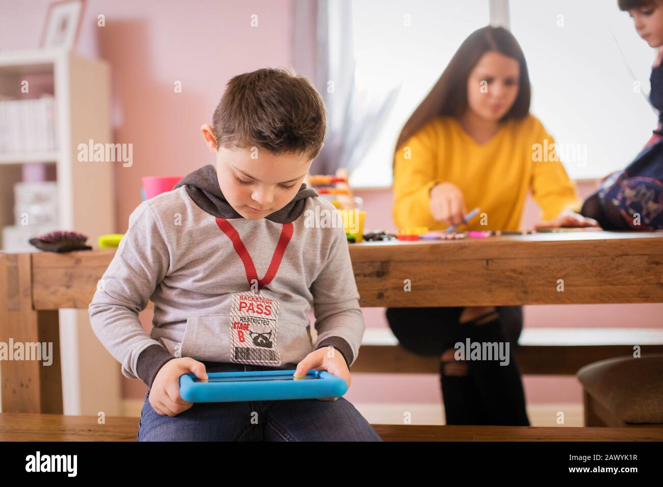 Junge mit Down-Syndrom mit digitalem Tablet im Speisesaal Stockfoto