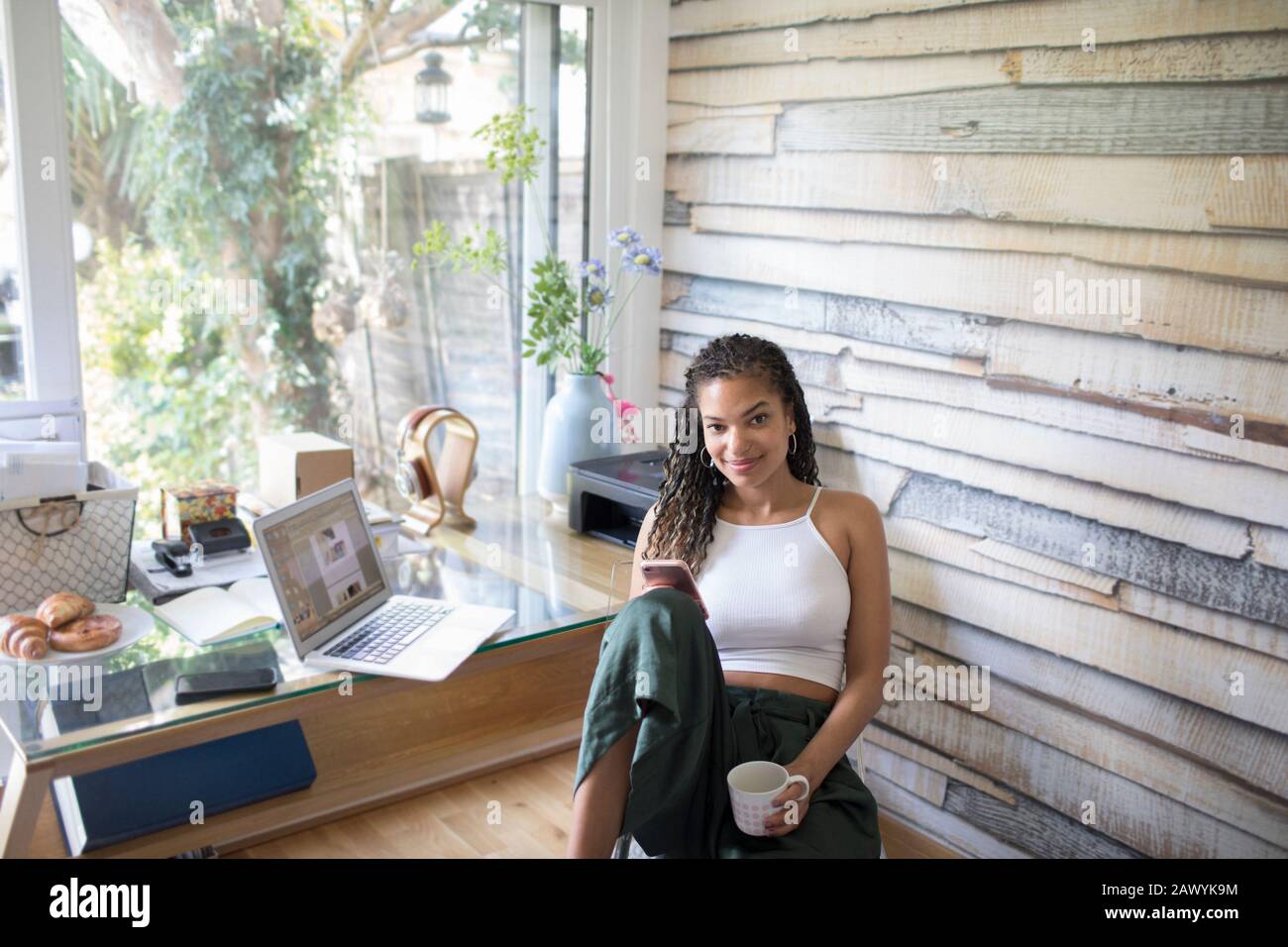 Portrait selbstbewusste junge Frau mit Smartphone im Büro Stockfoto