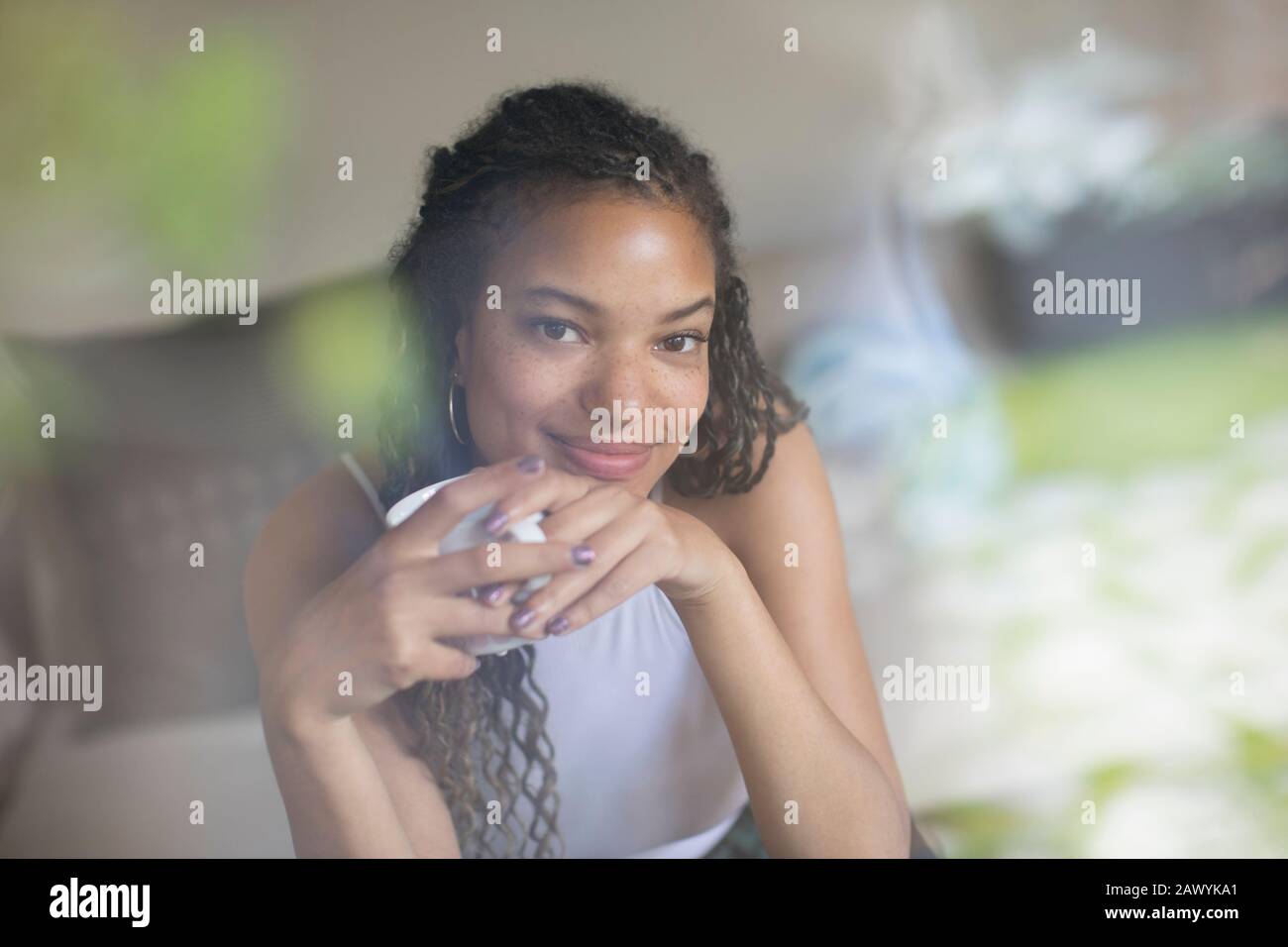 Portrait lächelnde, selbstbewusste junge Frau, die Kaffee trinkt Stockfoto