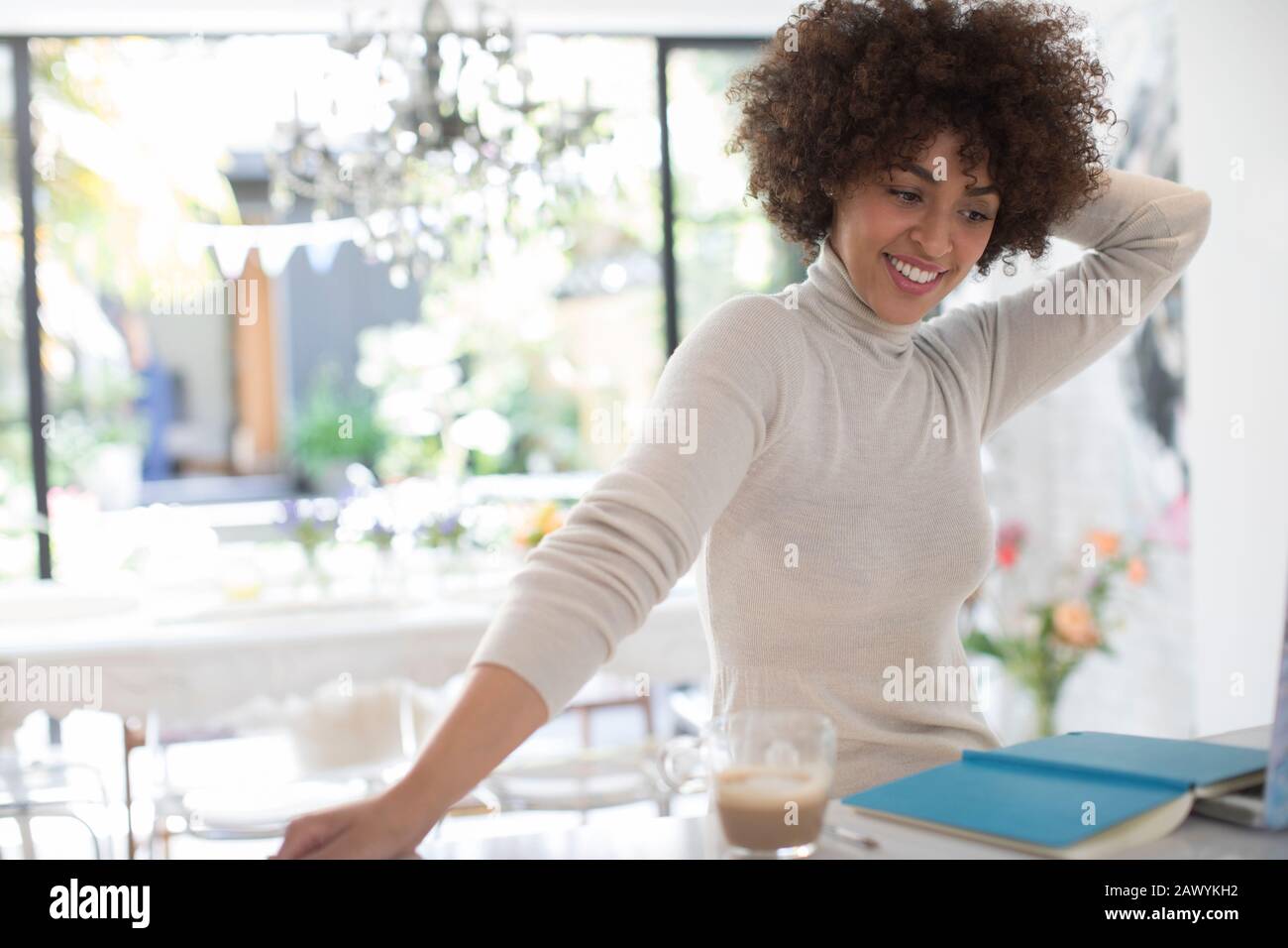 Fröhliche junge Freiberuflerin, die in der Küche arbeitet Stockfoto