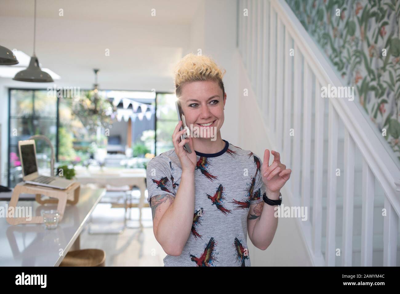 Lächelnde Freiberuflerin spricht in der Küche auf Smartphone Stockfoto