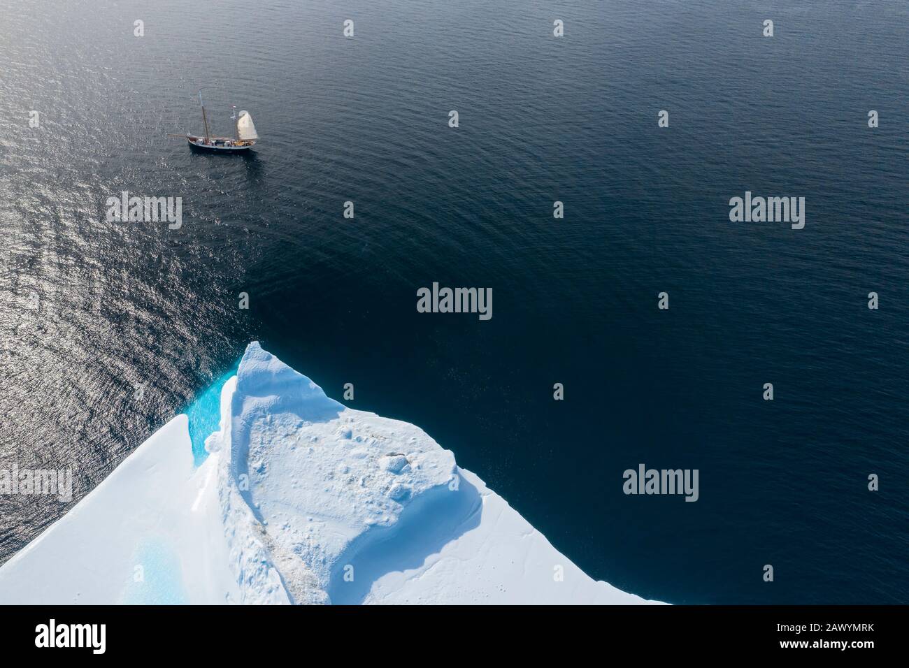 Schiff, das am Eisberg auf dem sonnigen Atlantik Grönlands vorbeisegelt Stockfoto