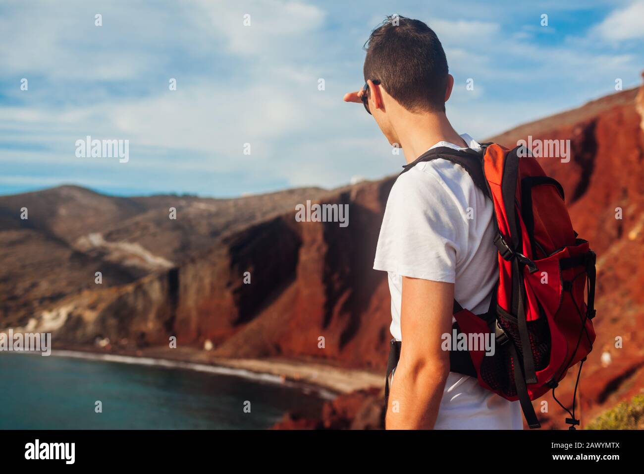 Tourist mit Blick auf den Roten Strand, die Landschaft der ägetischen Meere in Akrotiri, Santorini, Griechenland. Man-Rucksacktourist Stockfoto
