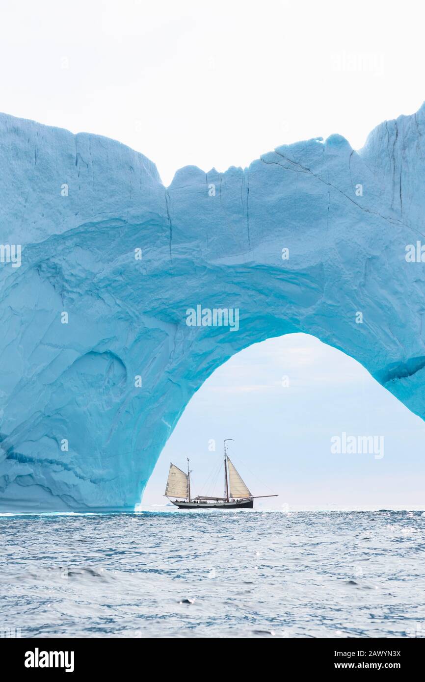 Schiff, das hinter dem Eisbergbogen auf dem Atlantik Grönland segelt Stockfoto