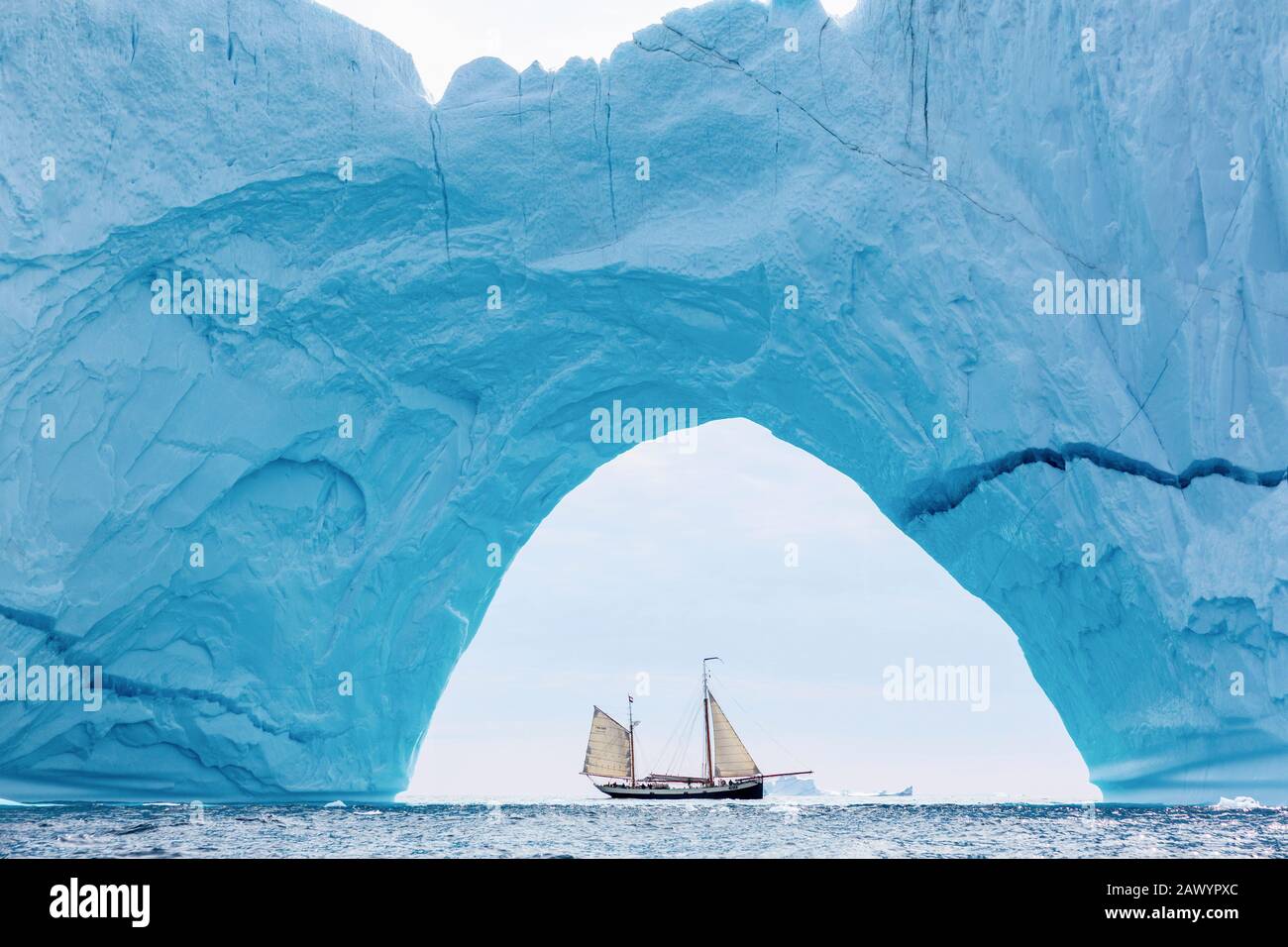 Schiff, das hinter dem majestätischen Eisbergbogen im Atlantik Grönland segelt Stockfoto