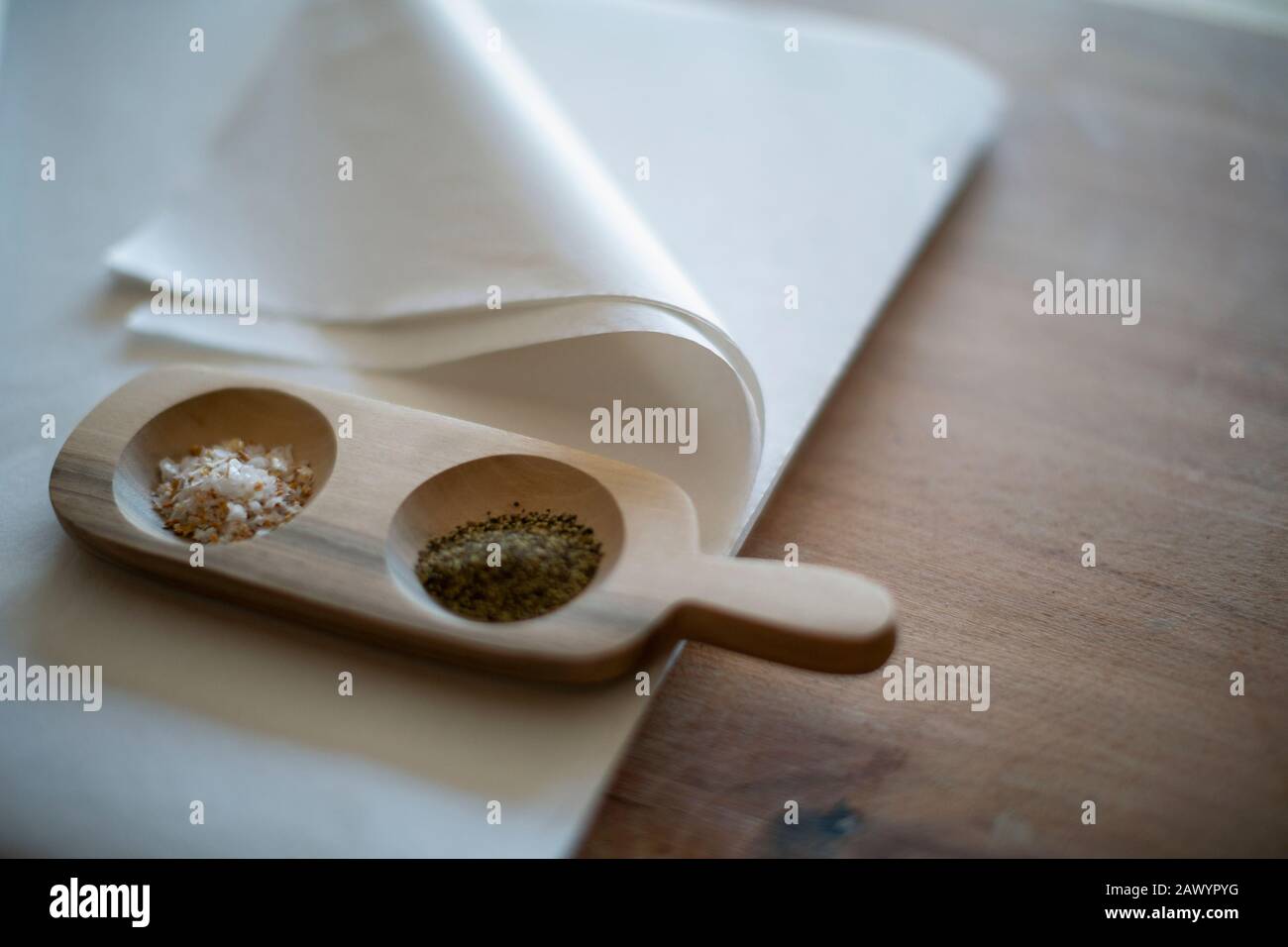 Feinschmeckersalz und Pfeffer in Holztablett auf Seidenpapier Stockfoto
