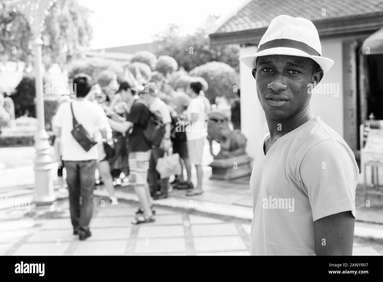 Junger afrikanischer Tourist mit einer Gruppe asiatischer Touristen im Wat Arun Tempel Stockfoto