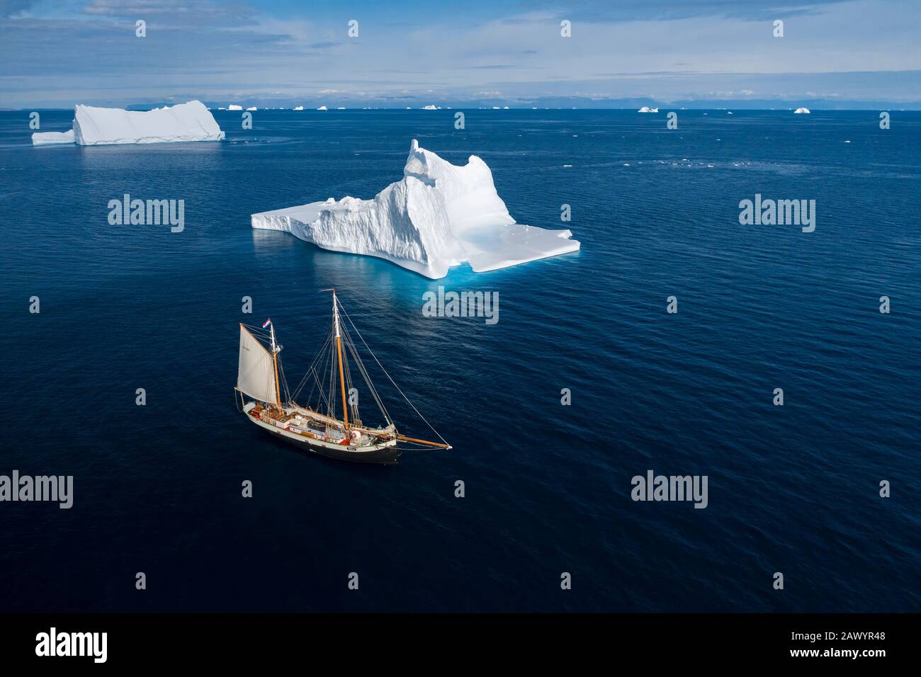 Schiff segelt an majestätischen Eisbergen auf dem sonnigen blauen Atlantischen Ozean Grönlands Stockfoto