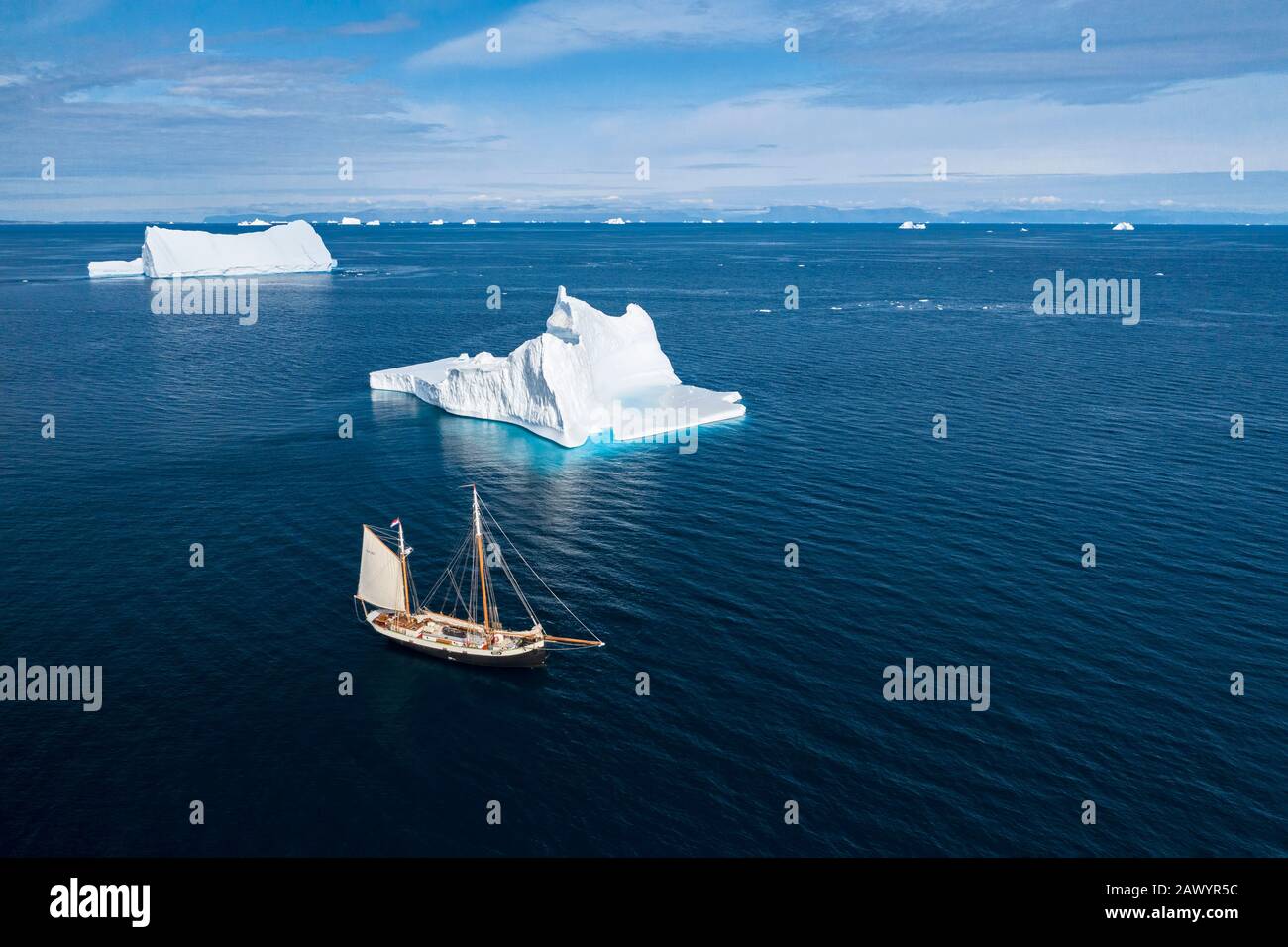 Schiff segelt an majestätischen Eisbergen auf dem sonnigen blauen Atlantischen Ozean Grönlands Stockfoto