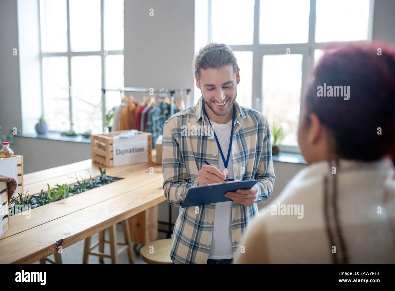 Junger Mann mit Bart steht lächelnd schriftlich. Stockfoto