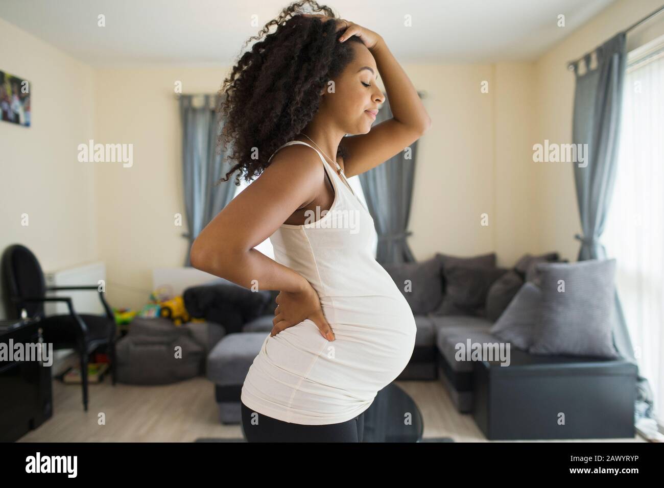 Müde junge schwangere Frau im Wohnzimmer Stockfoto