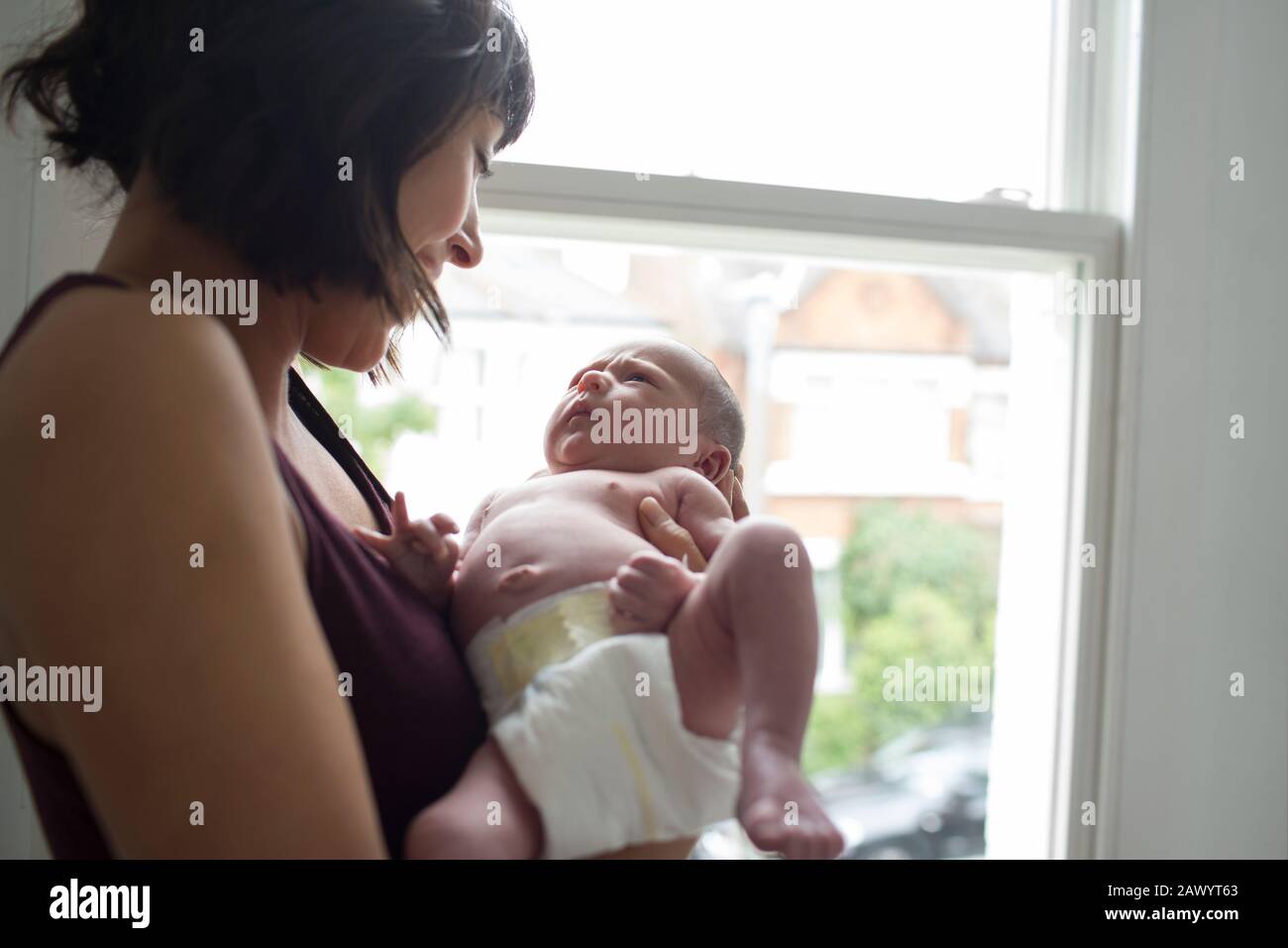 Mutter hält süßen neugeborenen Jungen am Fenster Stockfoto