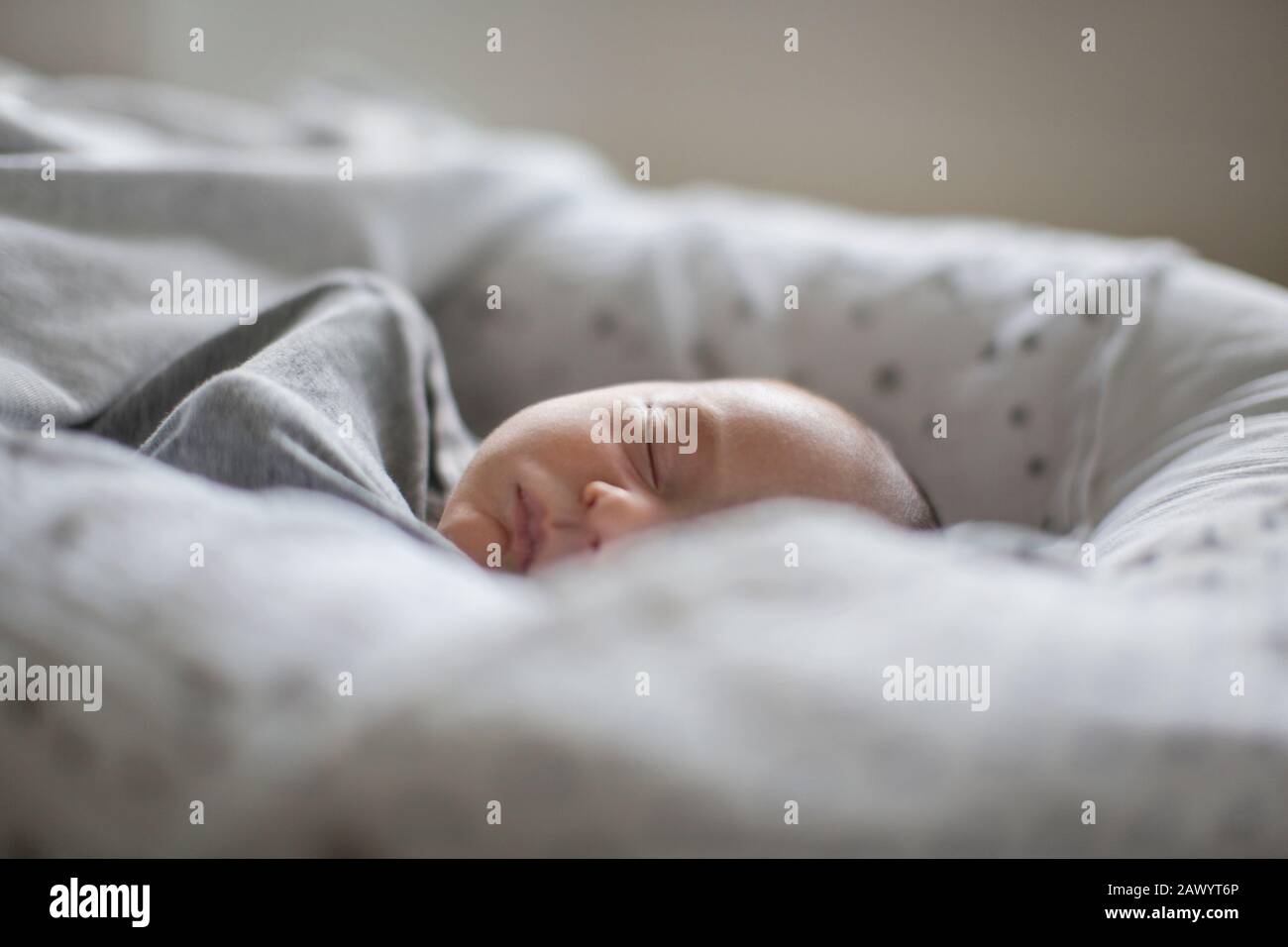 Müde unschuldige neugeborene Babyjunge, die im Korb des Moses schläfrig schlafen Stockfoto