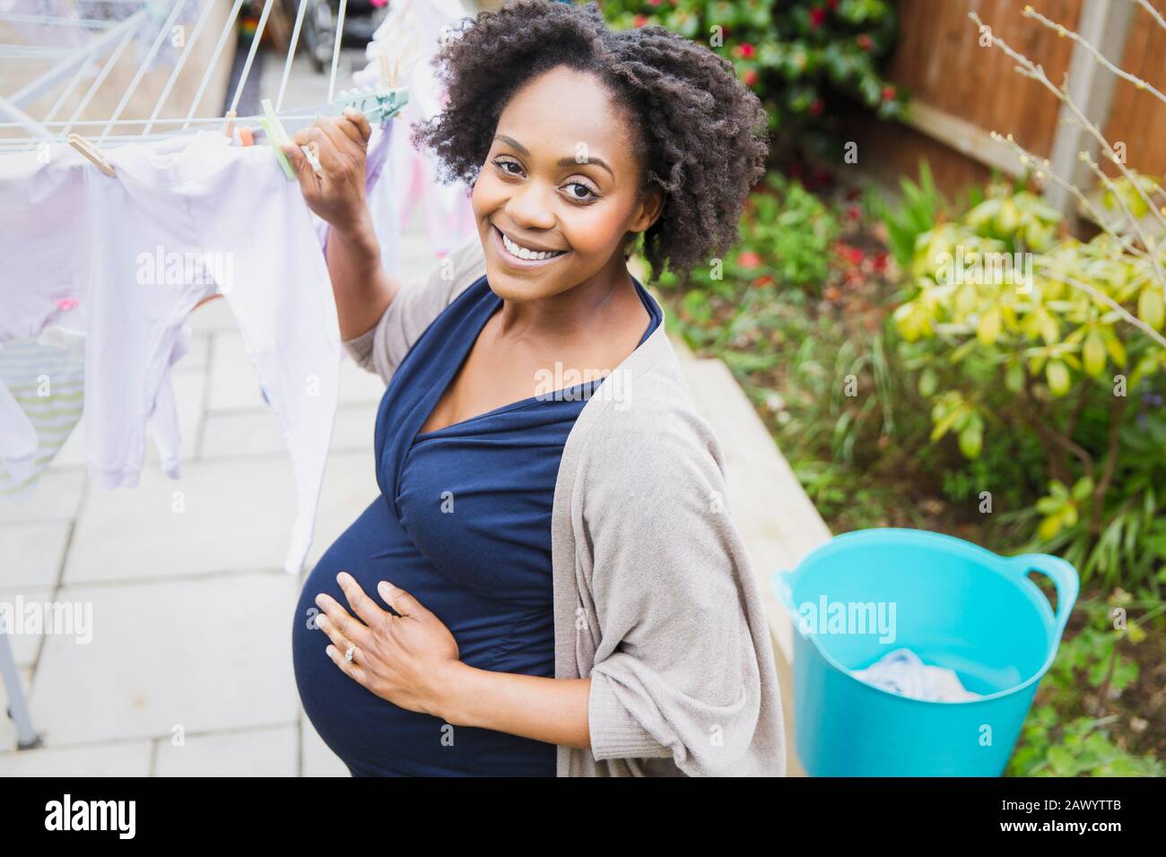 Portrait fröhliche schwangere Frau hängend Wäsche auf Wäscheleine Stockfoto