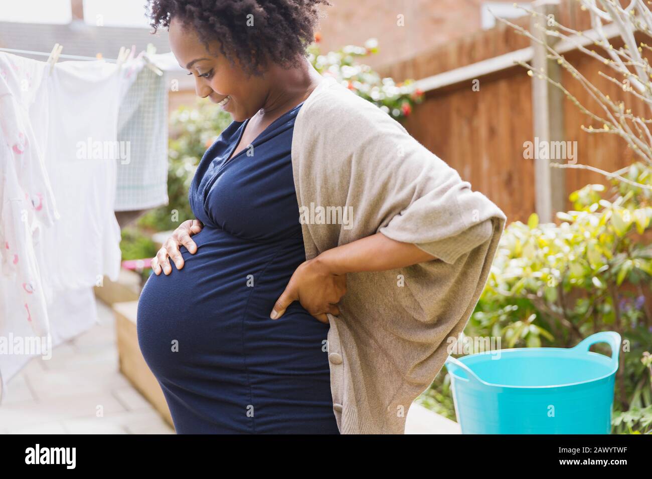 Glückliche schwangere Frau hängend Wäsche auf Wäscheleine Stockfoto