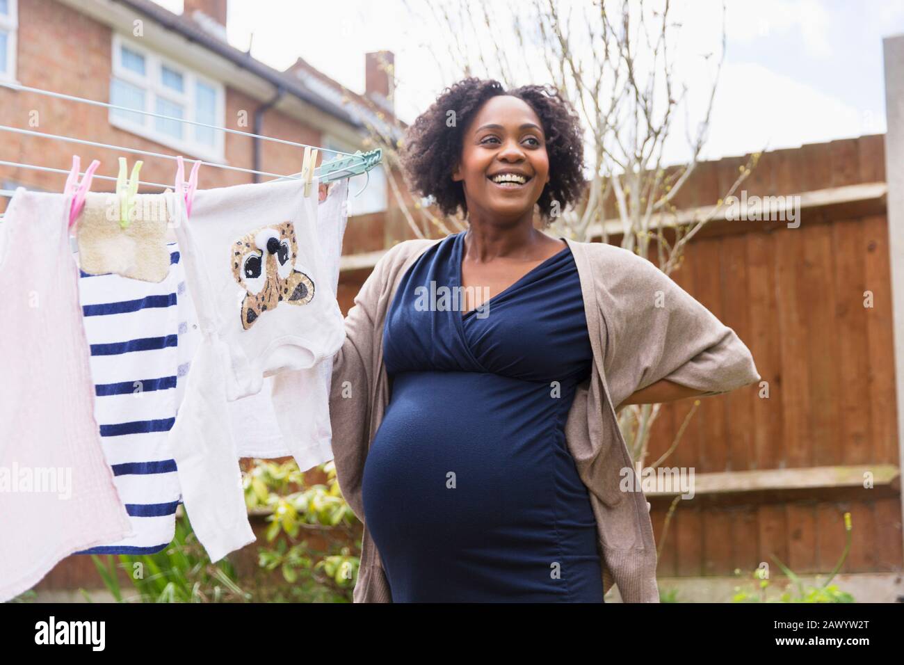 Glückliche schwangere Frau hängend Wäsche auf Wäscheleine im Garten Stockfoto