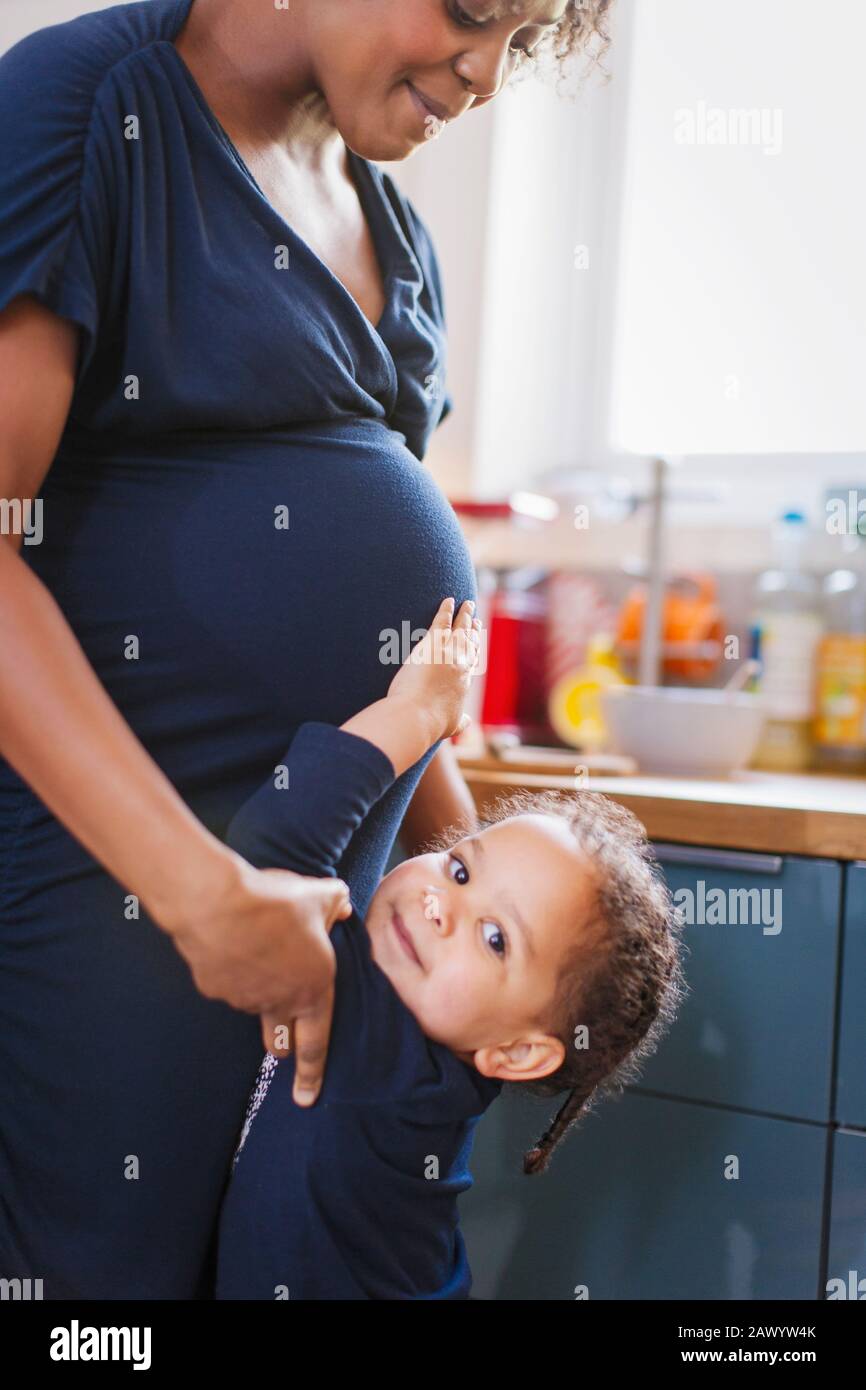 Portrait süße Tochter berührt schwangeren Muttermagen Stockfoto