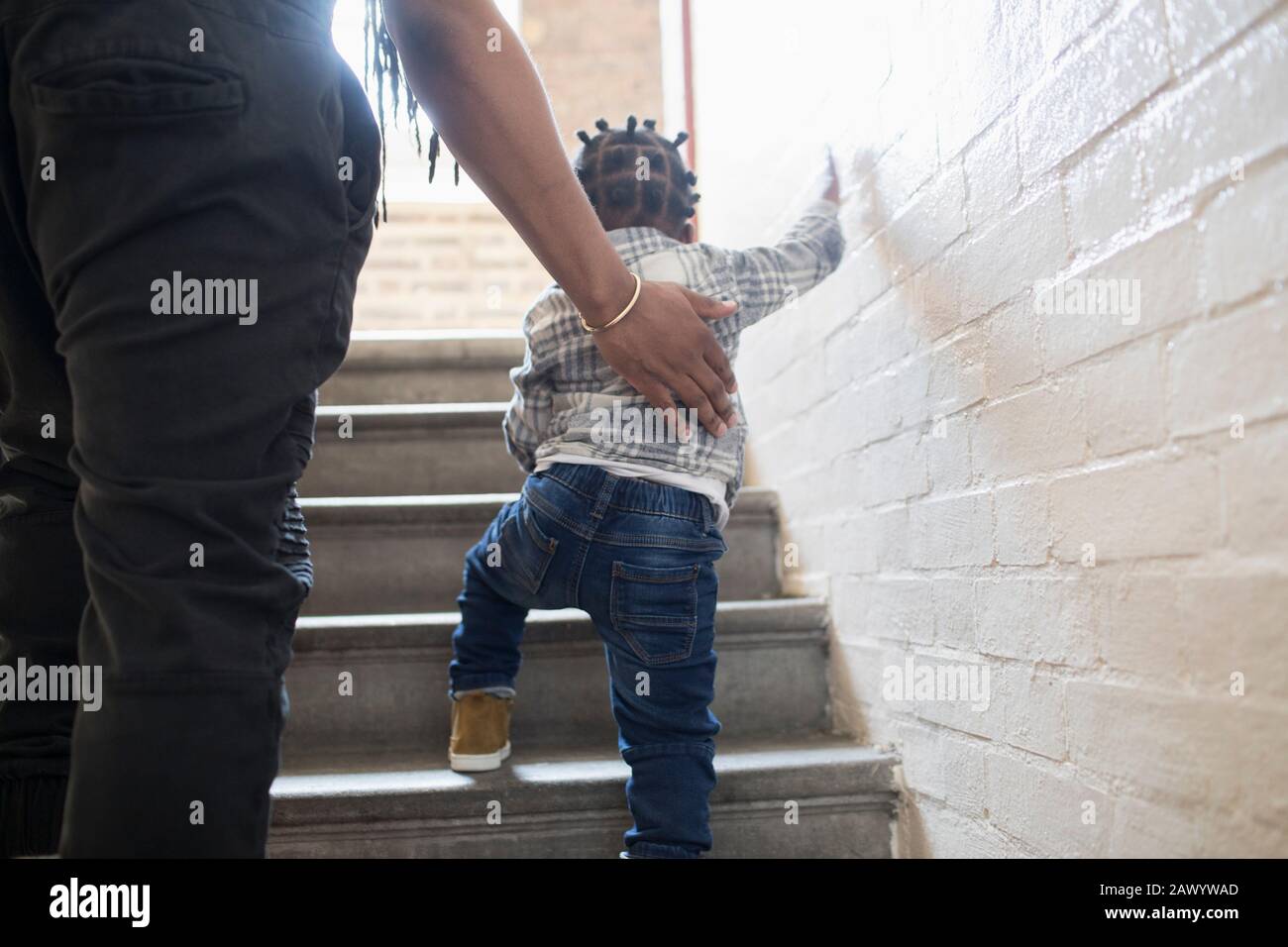 Vater hilft Kleinkindsohn, Treppen im Treppenhaus zu erklimmen Stockfoto