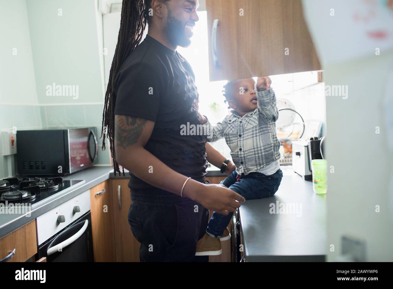 Vater und Kleinkind öffnen Schrank in der Wohnküche Stockfoto