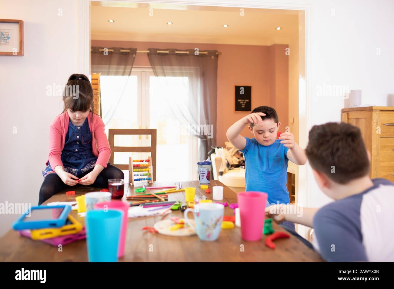 Brüder und Schwester spielen mit Spielzeug am Esstisch Stockfoto