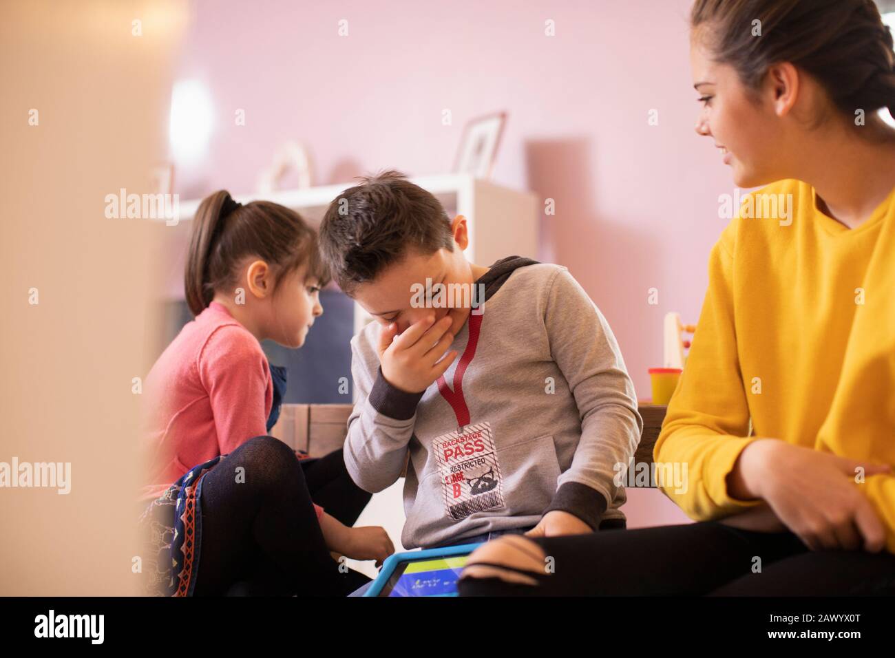 Lachender Junge mit Down-Syndrom mit Schwestern Stockfoto