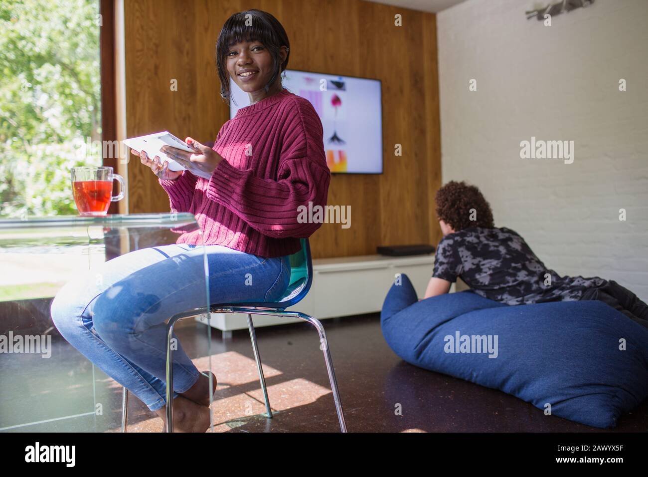 Portrait lächelnde junge Frau mit digitalem Tablet im Wohnzimmer Stockfoto