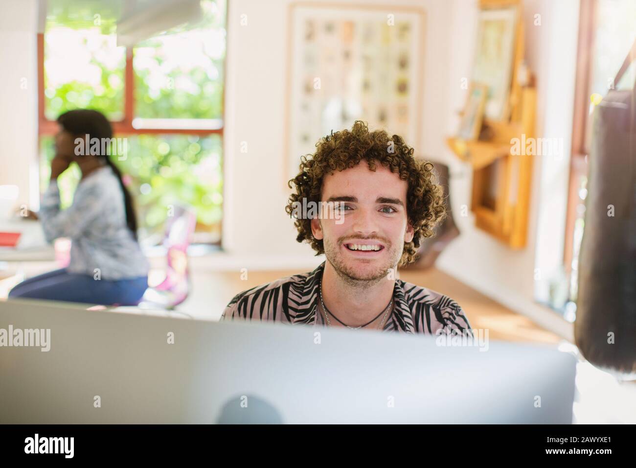Portrait fröhlicher junger Mann, der von zu Hause aus am Computer arbeitet Stockfoto