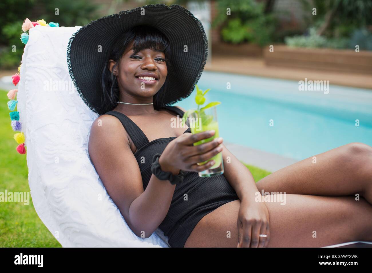 Portrait schöne junge Frau entspannend mit Cocktail am Pool Stockfoto