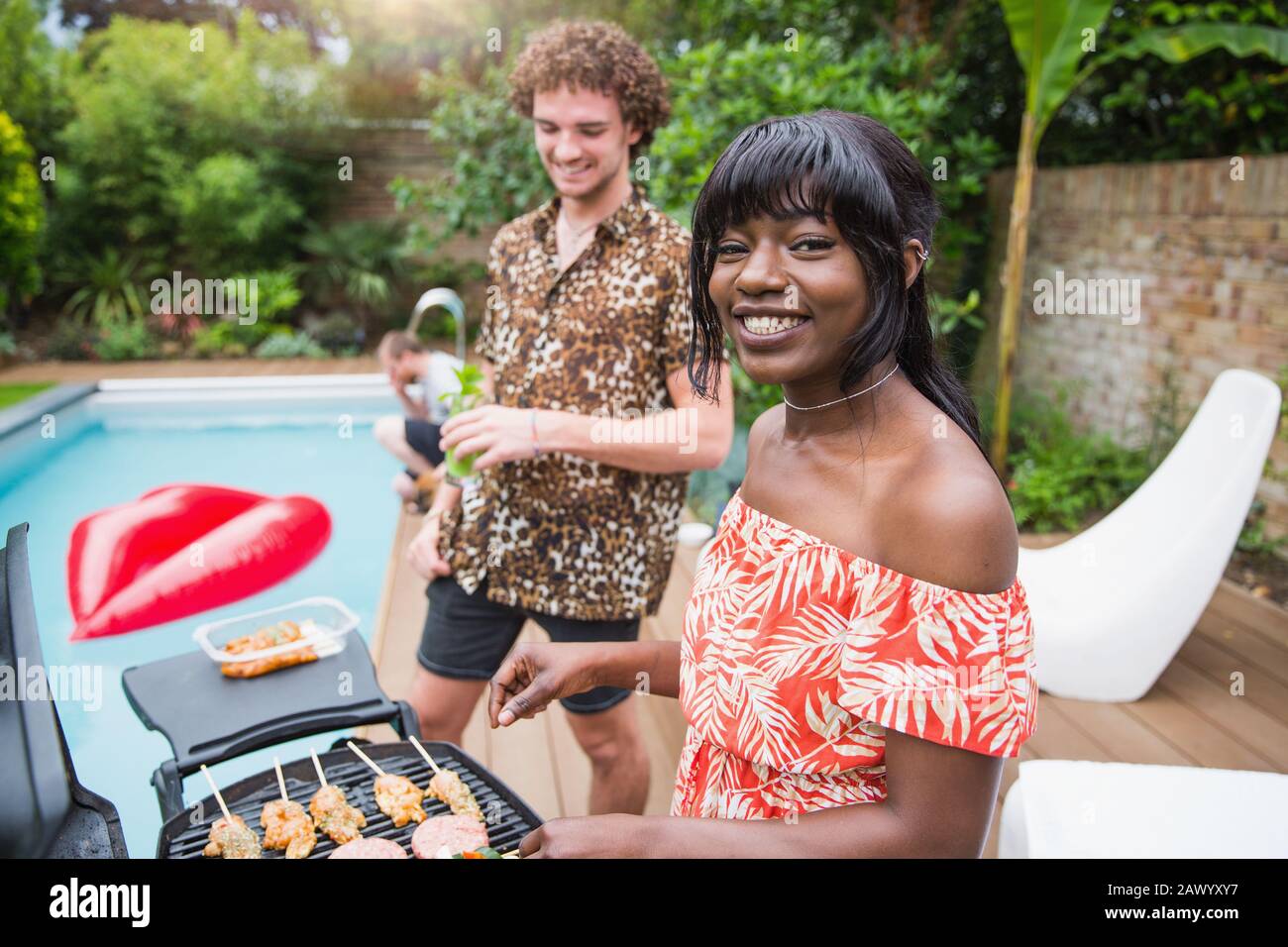 Portrait fröhliches junges multiethnisches Paar, das am Pool grillt Stockfoto