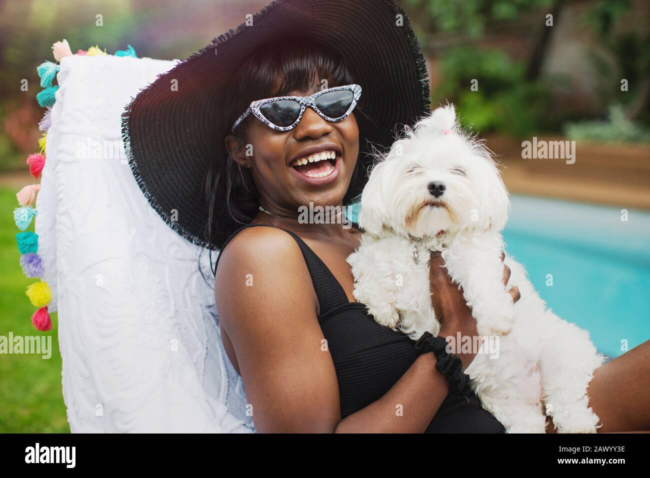 Portrait fröhliche junge Frau mit Hund am Pool Stockfoto