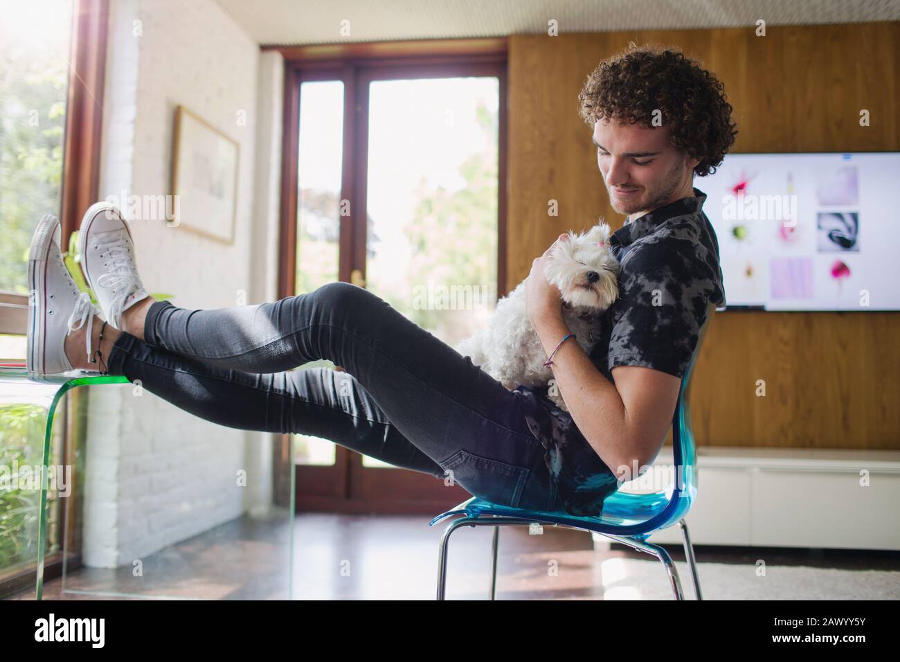 Junger Mann streichender Hund im Heimbüro Stockfoto