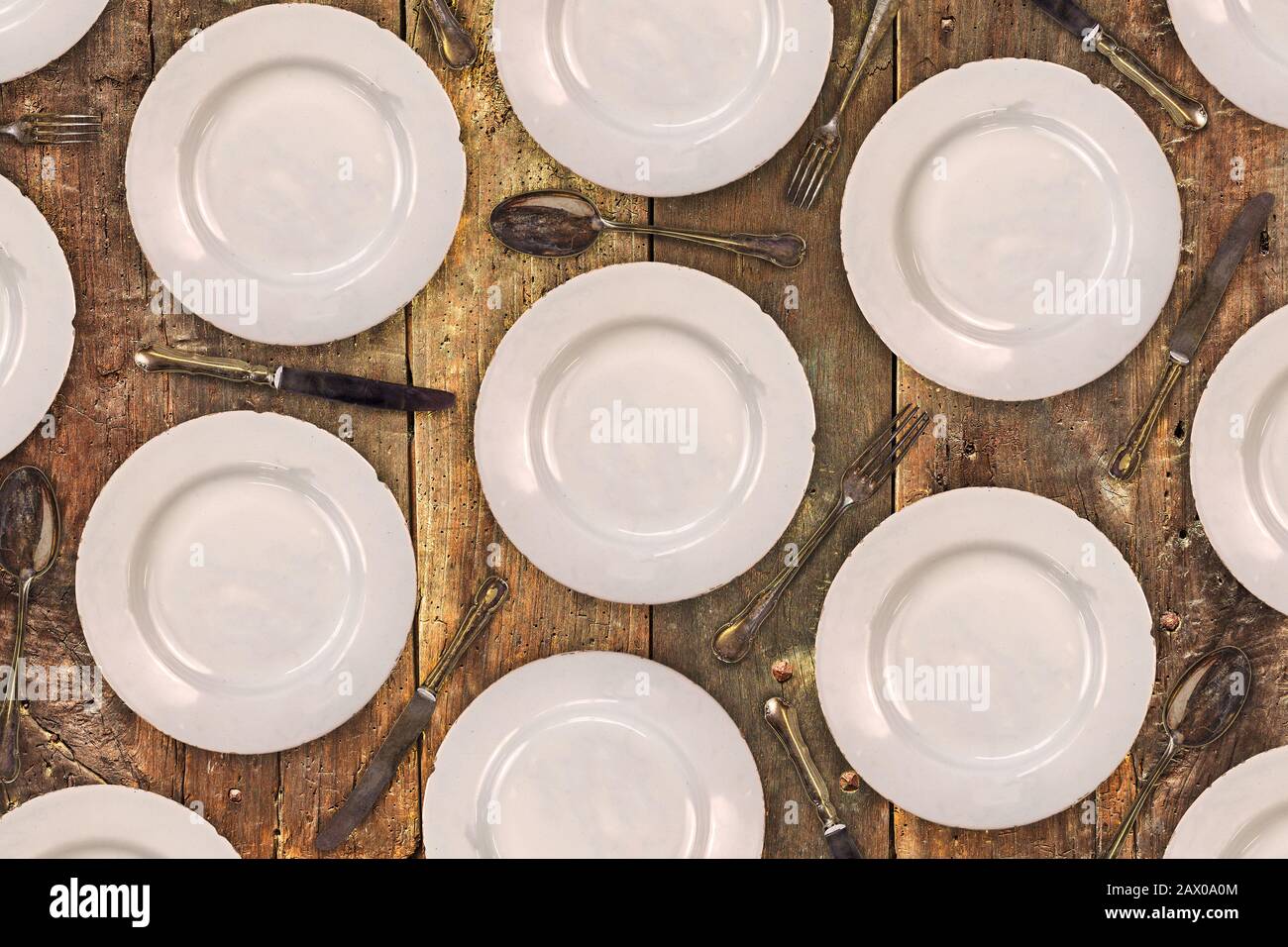 Muster aus Vintage-Dinner-Platten, Messern, Gabeln und Löffeln auf einem alten Holztisch Stockfoto