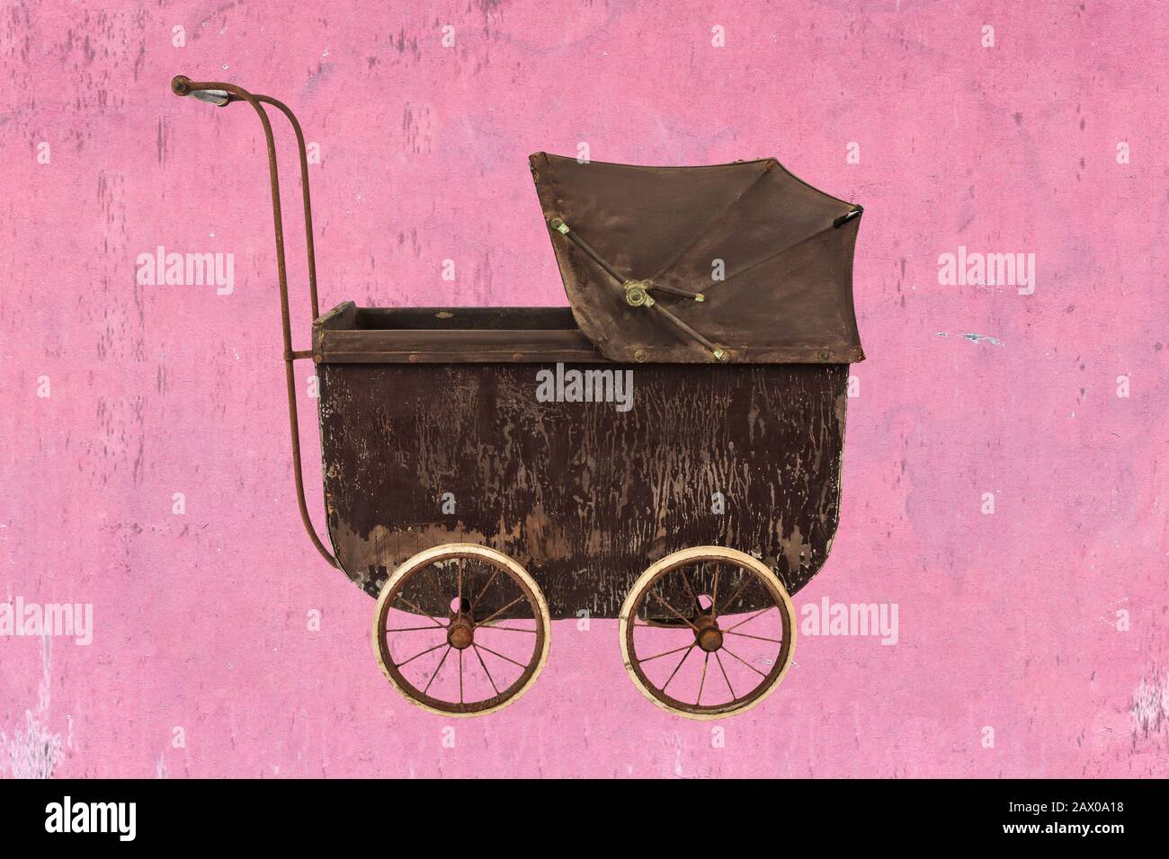 Brauner Kinderwagen in Vintage-Braun vor einem rosafarbenen, erodierten Hintergrund Stockfoto