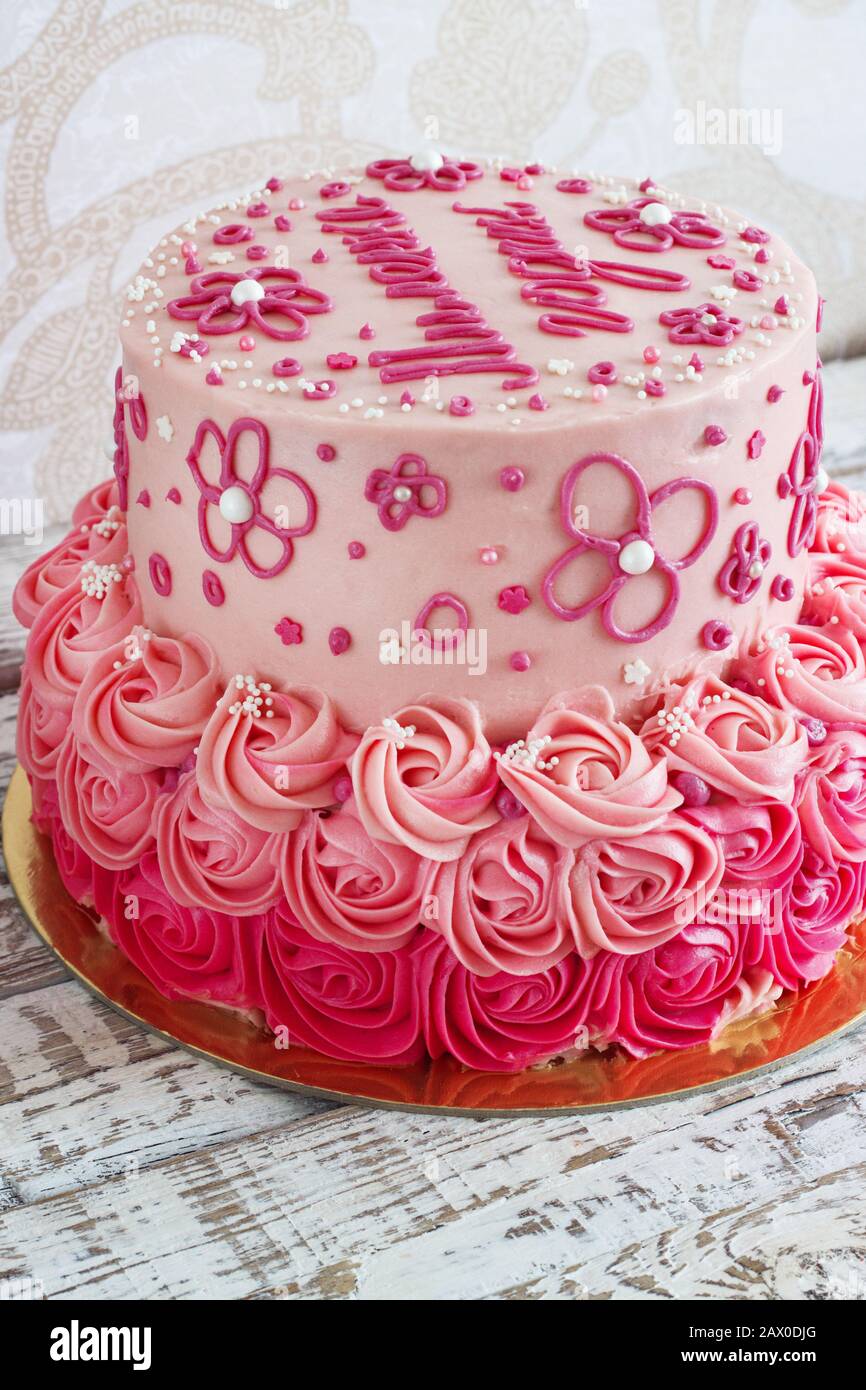 Festlicher, rosafarbener Kuchen für ein Mädchen mit cremefarbenen Rosen auf hellem Hintergrund Stockfoto