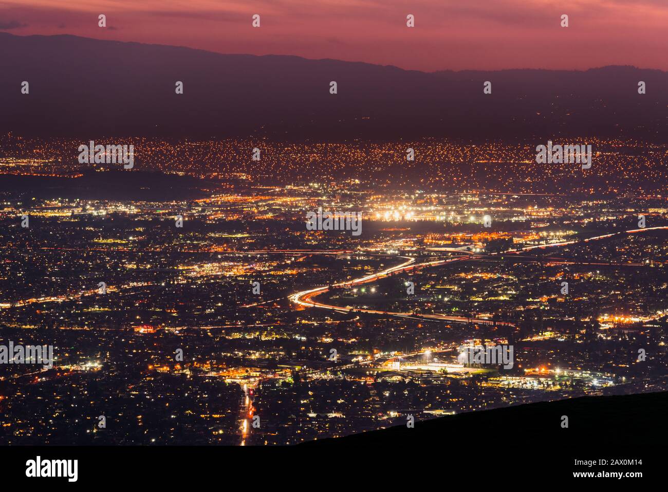 Panorama-Nachtblick über die Ausbreitung der Stadt in San Jose, Silicon Valley, Kalifornien; Sichtbarer Lichtpfad links von Autos, die auf einer der Autobahnen fahren; Long ex Stockfoto