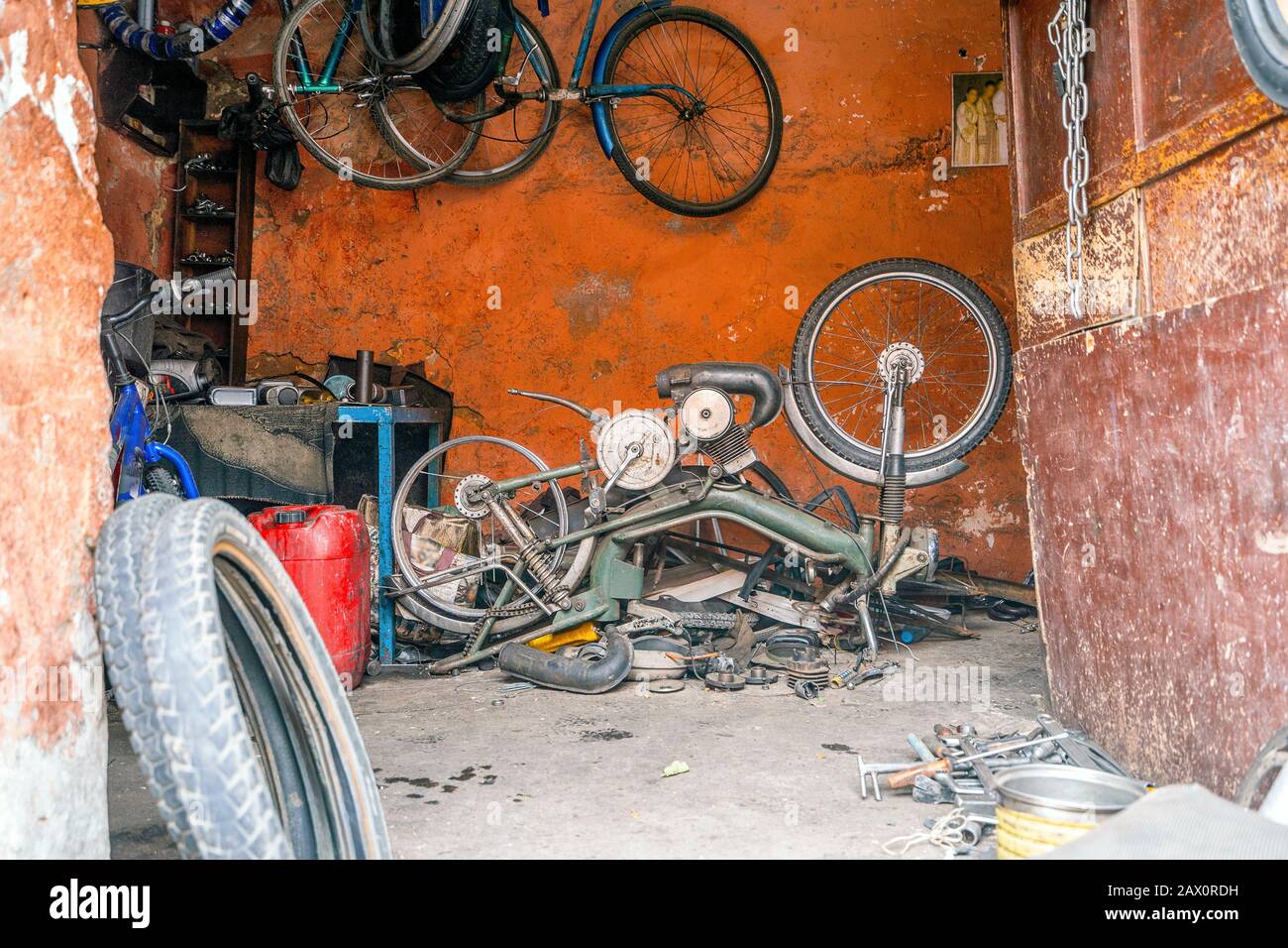 Defektes Motorrad in der unordentlichen orangefarbenen Garage, Marrakesch, Marokko Stockfoto