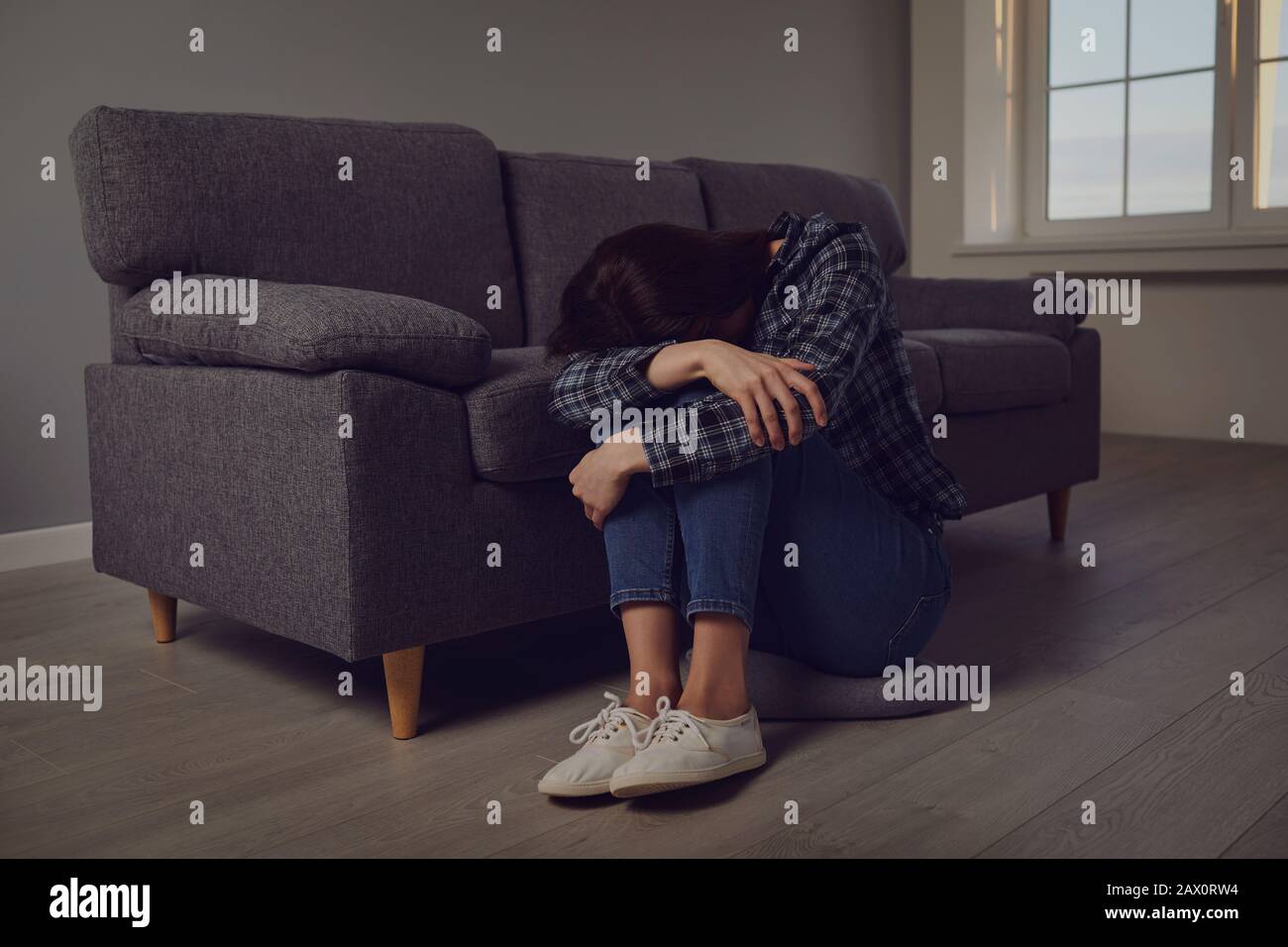 Eine unglücklich einsame depressive Frau sitzt allein in einem Raum Stockfoto