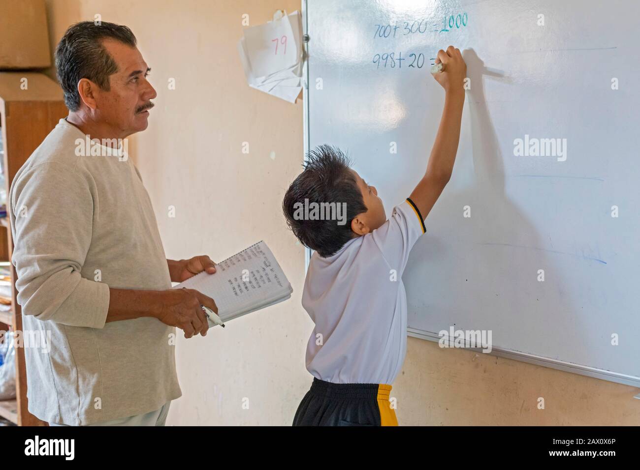 Brisas de Zicatela, Oaxaca, Mexiko - EIN Lehrer beobachtet, wie ein Schüler in einer dritten Klasse an der Escuela Primaria Tierra y Liberdad, einer PRI, ein Mathematikproblem macht Stockfoto