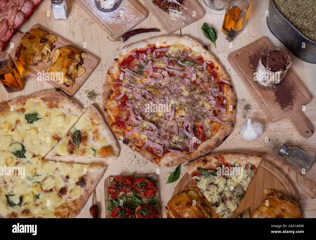 Luftaufnahme von köstlichen Sorten frisch zubereiteter neapolitanischer Mittelmeer-Pizza und Tapas auf Holztisch. Stockfoto