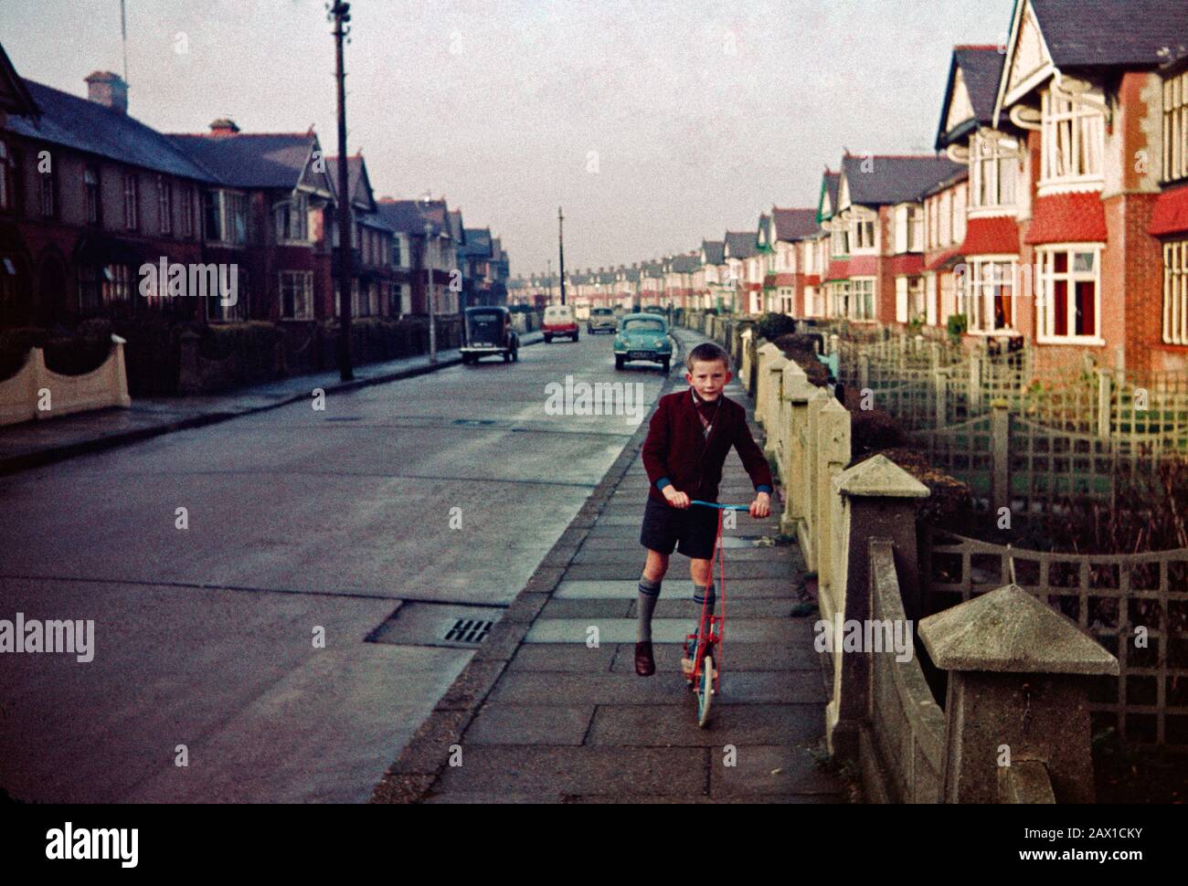 Siebenjähriger Junge auf einem Roller am Weihnachtstag 1961 in der Chatsworth Avenue, Cosham, Portsmouth. Beachten Sie, wie wenige Autos es gibt. Stockfoto