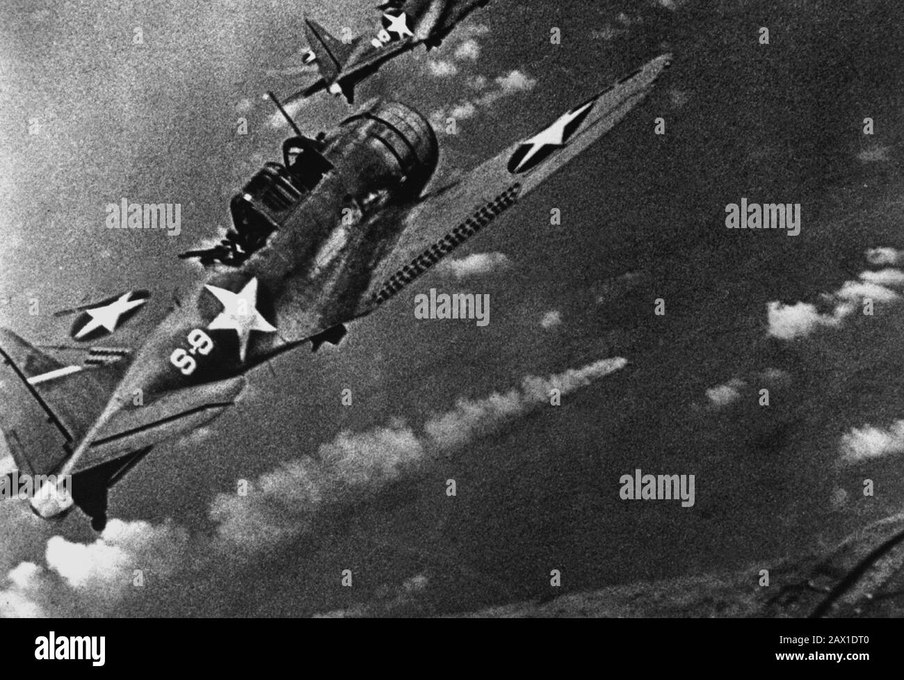 JUNI, USA: ZWISCHENKAMPF . Marinekämpfer während des Angriffs auf die japanische Flotte vor Midway vom 4. Bis 6. Juni 1942. Im Zentrum ist ein brennendes japanisches Schiff zu sehen. (Navy) Douglas SBD-3 "Dundless"-Sturzkampfbomber der US-Navy aus dem Pfadfindergeschwader VS-8 des Flugzeugträgers USS Hornet (CV-8), der sich dem brennenden japanischen schweren Kreuzergeschwader MIKUMA nähert, um während der Schlacht um Midway, 6. Juni 1942, den dritten Angriffssatz auf sie zu machen. Mikuma war zuvor von Streiks von Hornet und USS Enterprise (CV-6) getroffen worden, ließ sie tot im Wasser liegen und tödlich verunglückte. Beachten Sie, dass Bomben unter t hängen Stockfoto