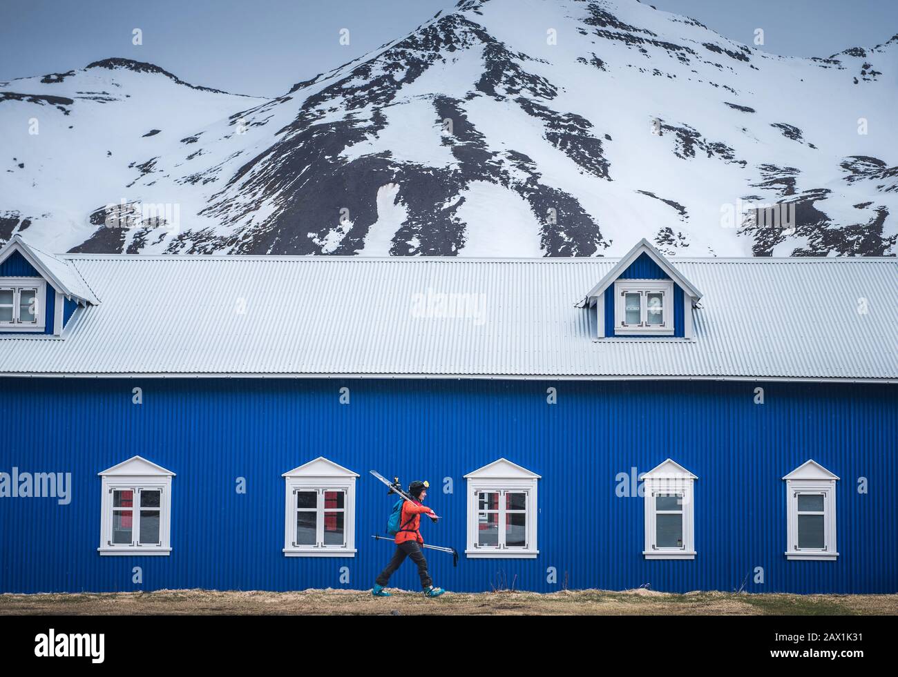 Eine Frau geht vor einem blauen Gebäude in Island Stockfoto