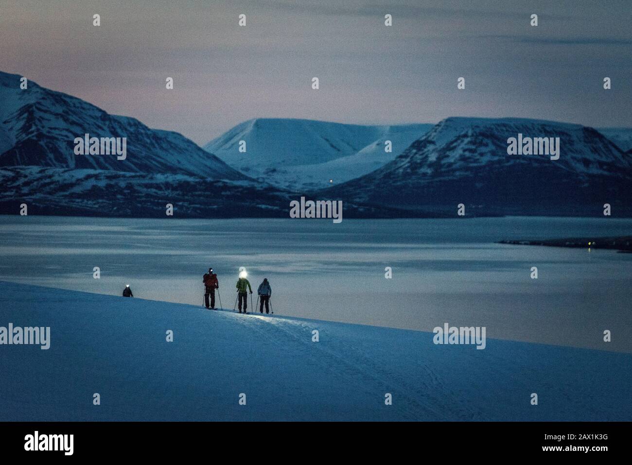 Eine Gruppe von 3 Personen Skier bei Sonnenaufgang mit Meer und Bergen dahinter Stockfoto