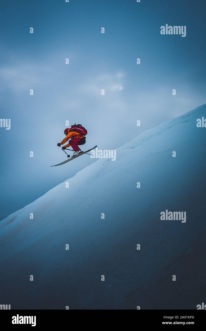 Skifahrer, die mit dem Himmel hinter ihm vom Skisprungschanze abspringen Stockfoto