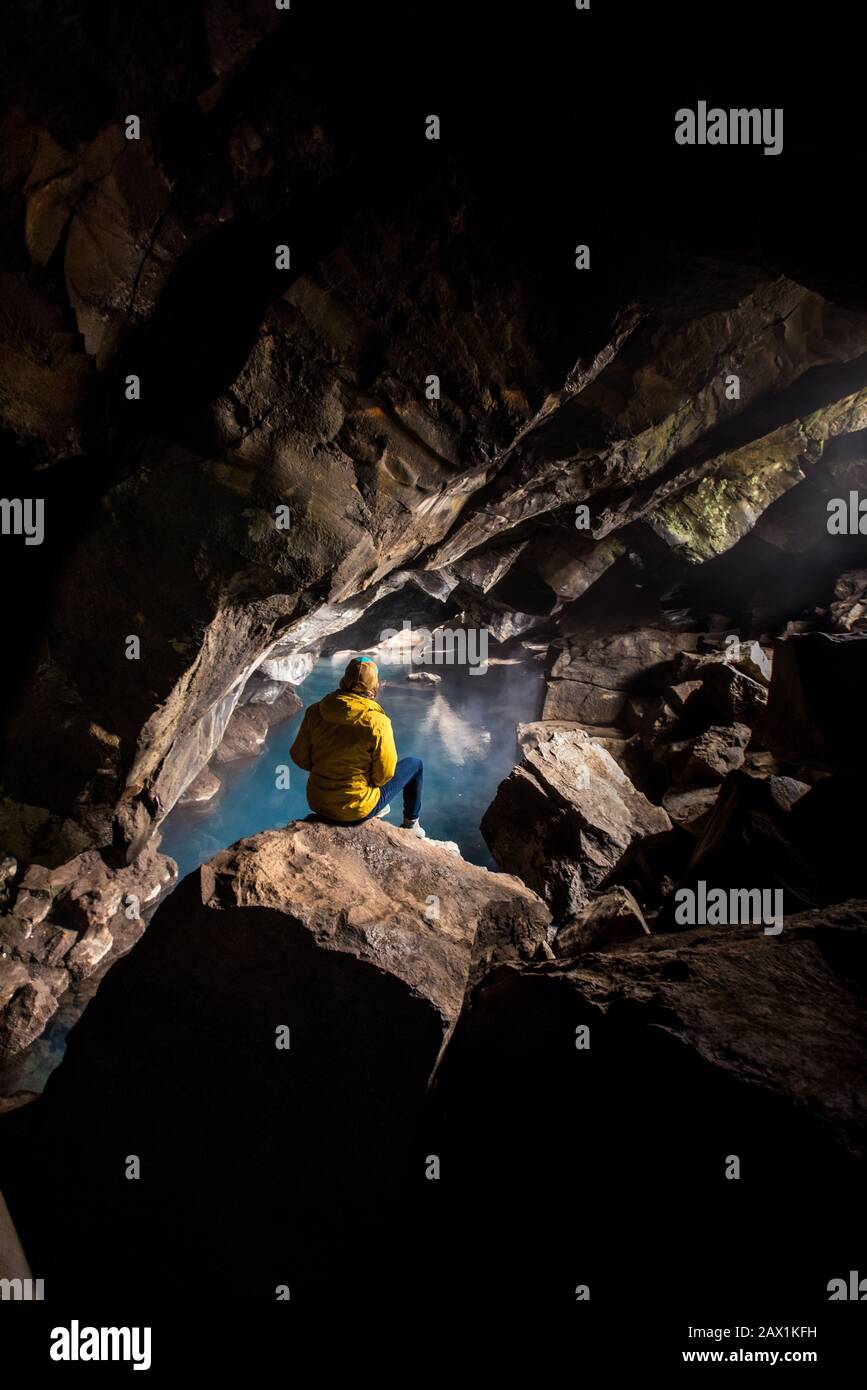 Frau sitzt vor dem Thermalbad in der Höhle Stockfoto