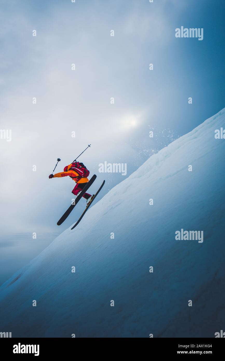 Mann, der mit Sonne und Himmel hinter ihm vom Skisprungschanze abfliegt Stockfoto