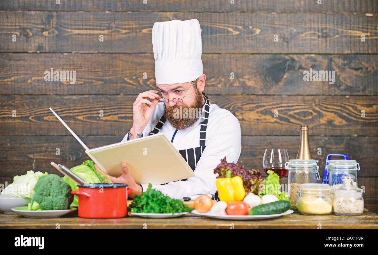 Das Rezept folgen. konzentrierte bärtiger Mann Kochen in der Küche. Diät Bio- Lebensmittel. Frisches Gemüse. Vitamin. Mann mit Küchenutensilien. Professionelle che Stockfoto