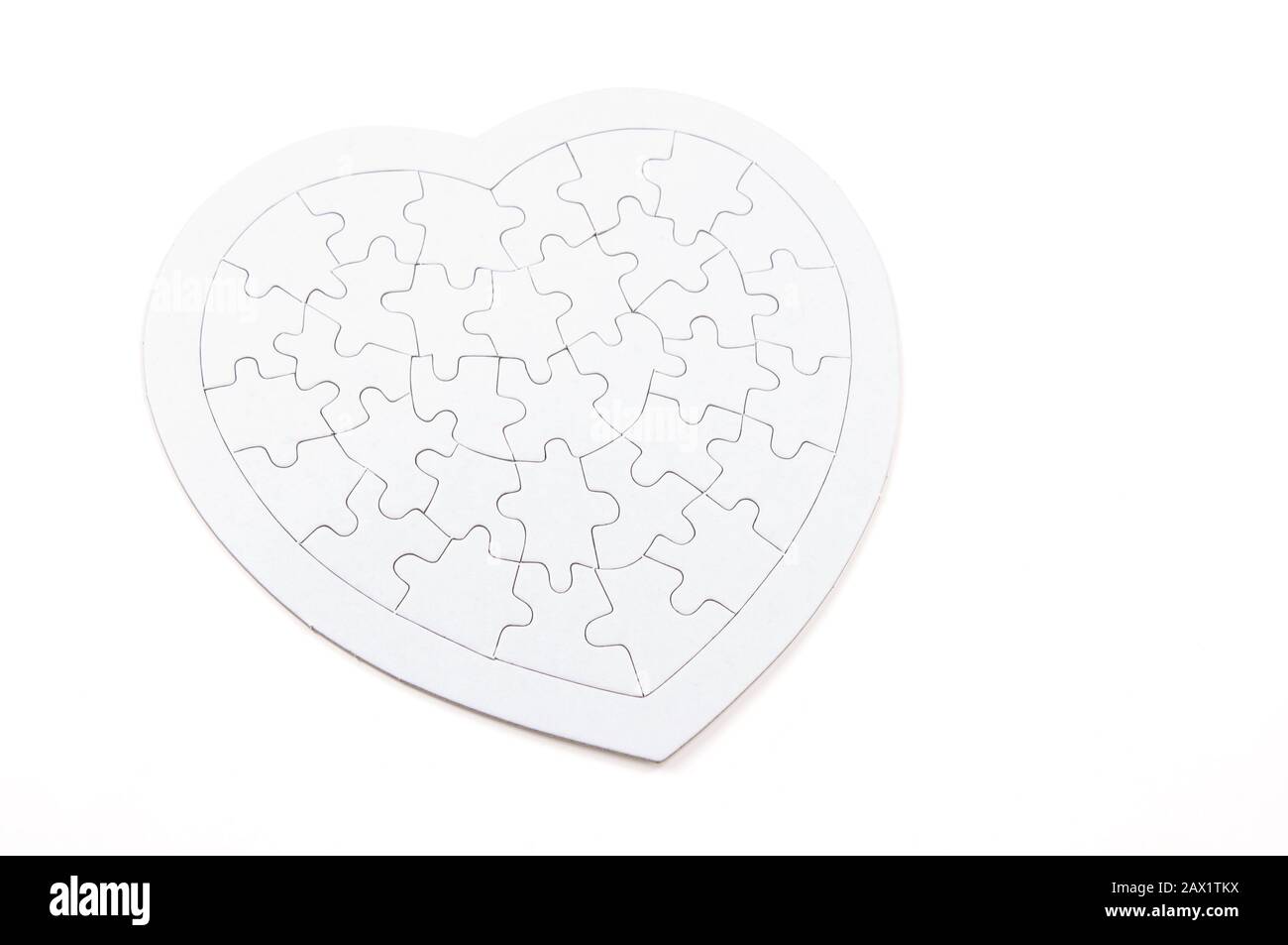 Pappe Herz mit Puzzle-Muster Ausschnitte in einer Stilllebenansicht auf weißem Hintergrund Stockfoto