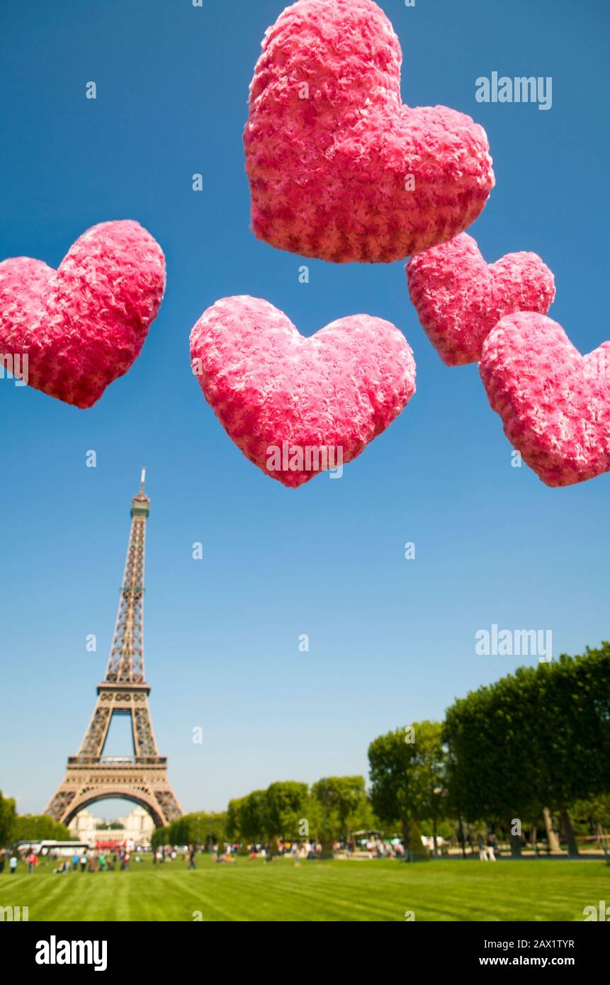 Unscharfe pinkfarbene Valentinstag Herzen schweben am blauen Himmel über dem Eiffelturm, Paris, Frankreich Stockfoto